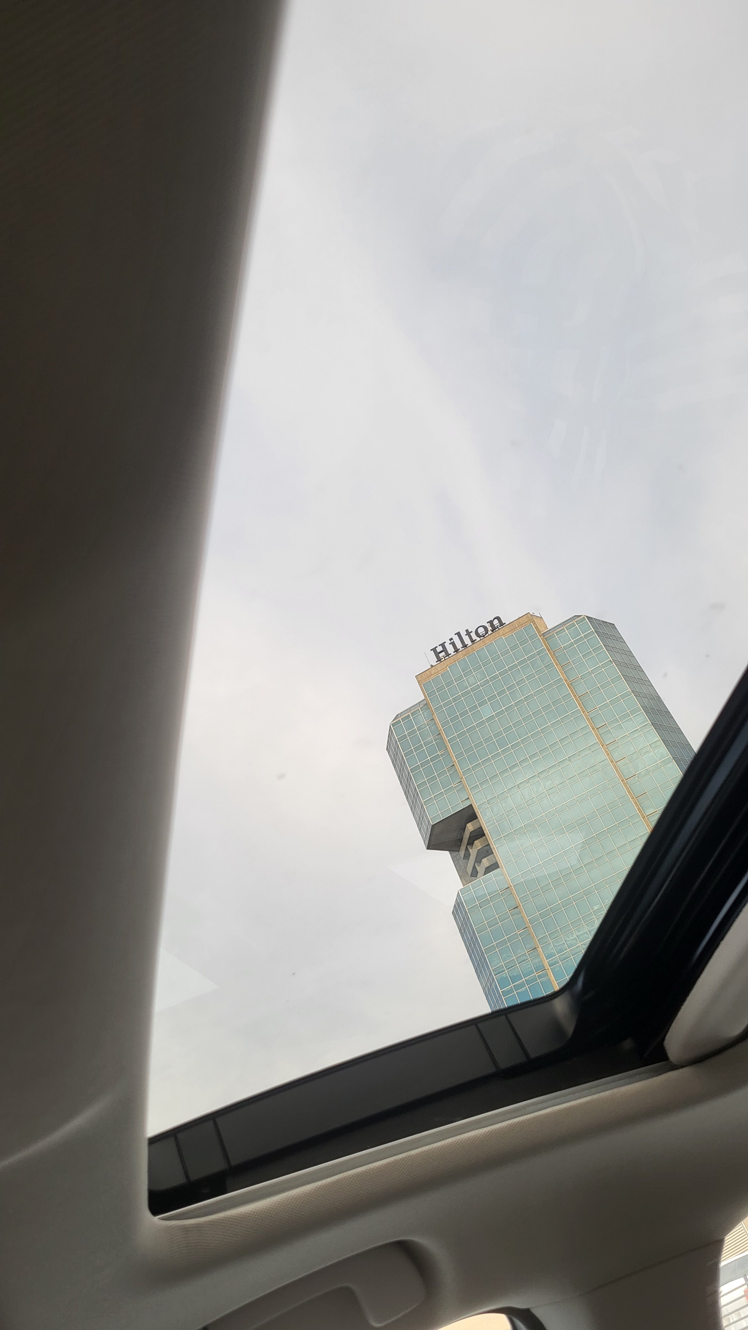  Through the sunless sunroof of her car, the Hilton Alexandria Mark Center hotel looms tall. It’s weathered concrete verticality almost disappears against the grey skies. Brutalist in appearance, one can scarcely believe it will house some of the mos
