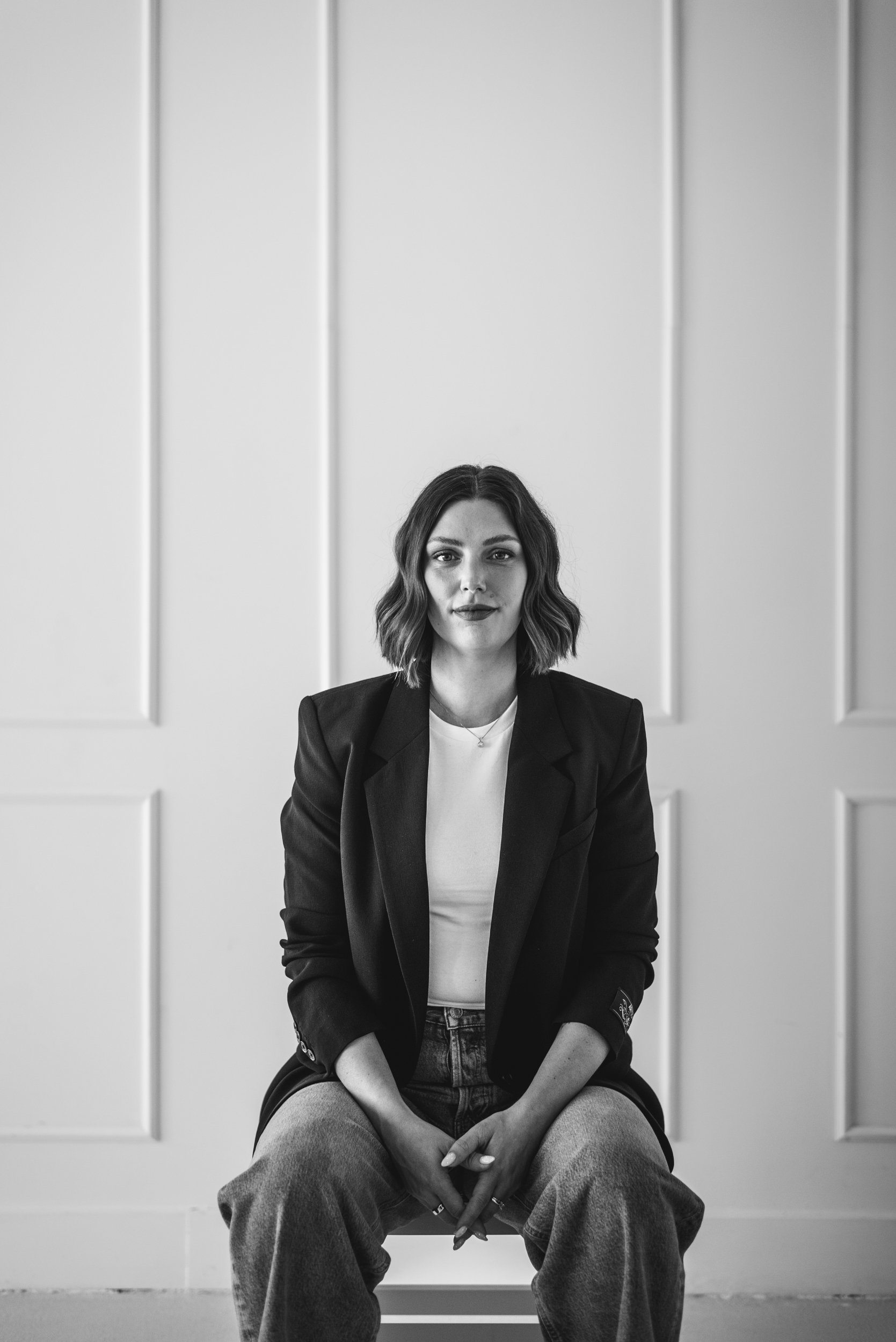 Black and white image of a woman sitting on a stool.