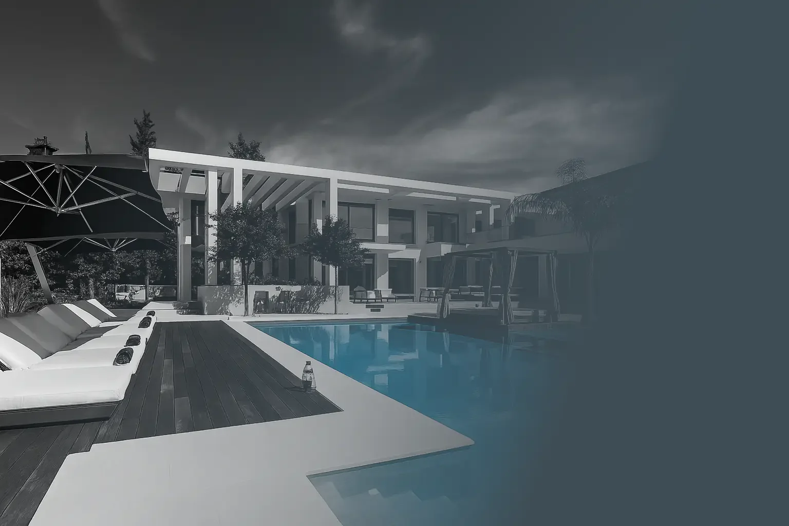 Modern backyard in Greece with swimming pool, lounge chairs, shaded umbrella, and contemporary house in the background.