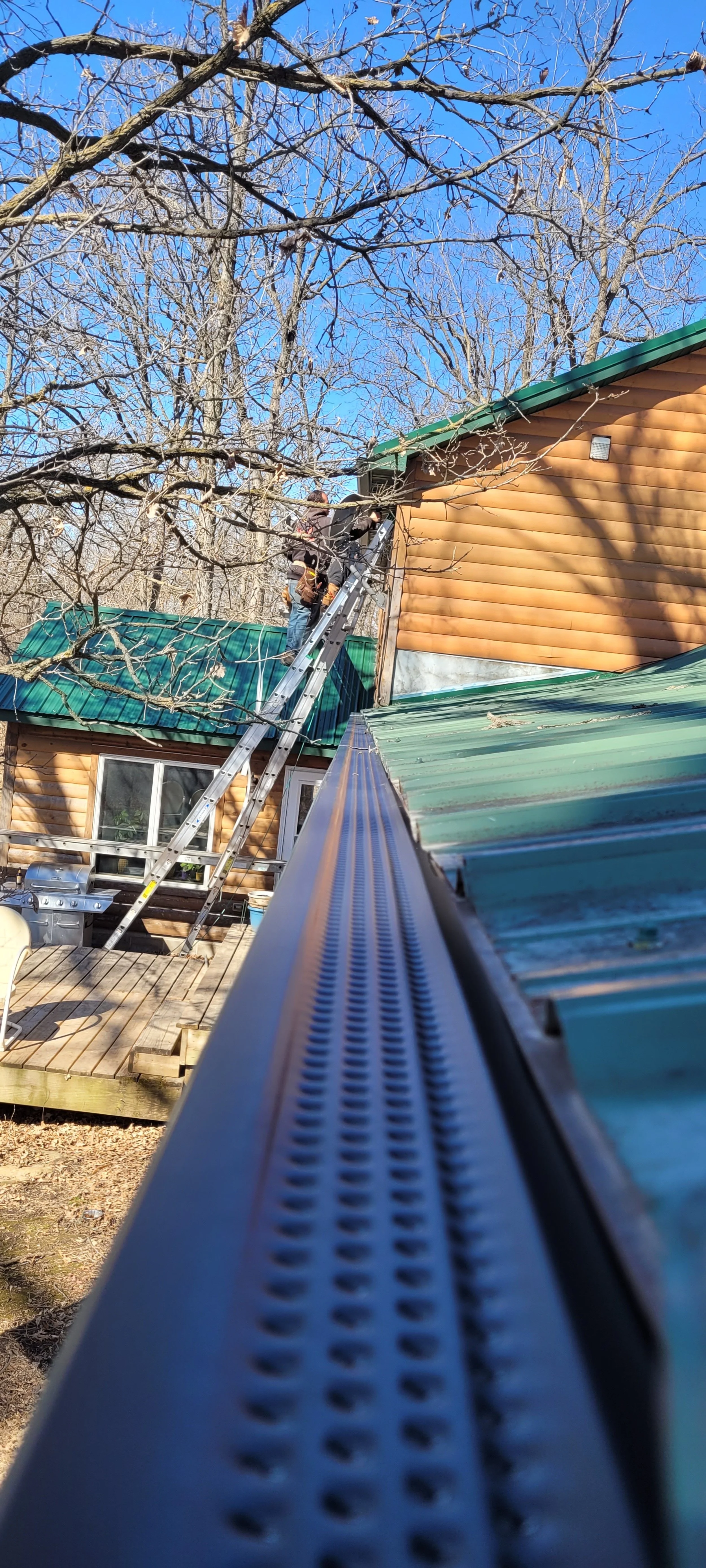 Black high flow gutter cover on a house with green metal roof