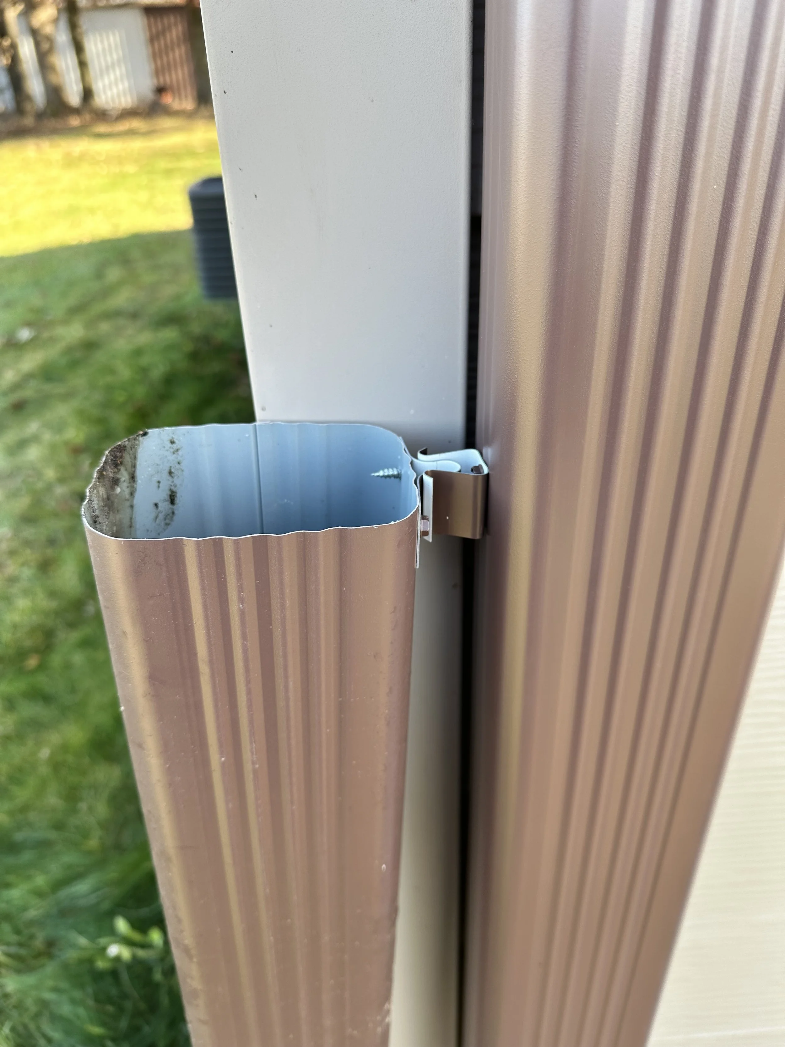 Side view of a wind clip retention clasp holding up a hinged downspout