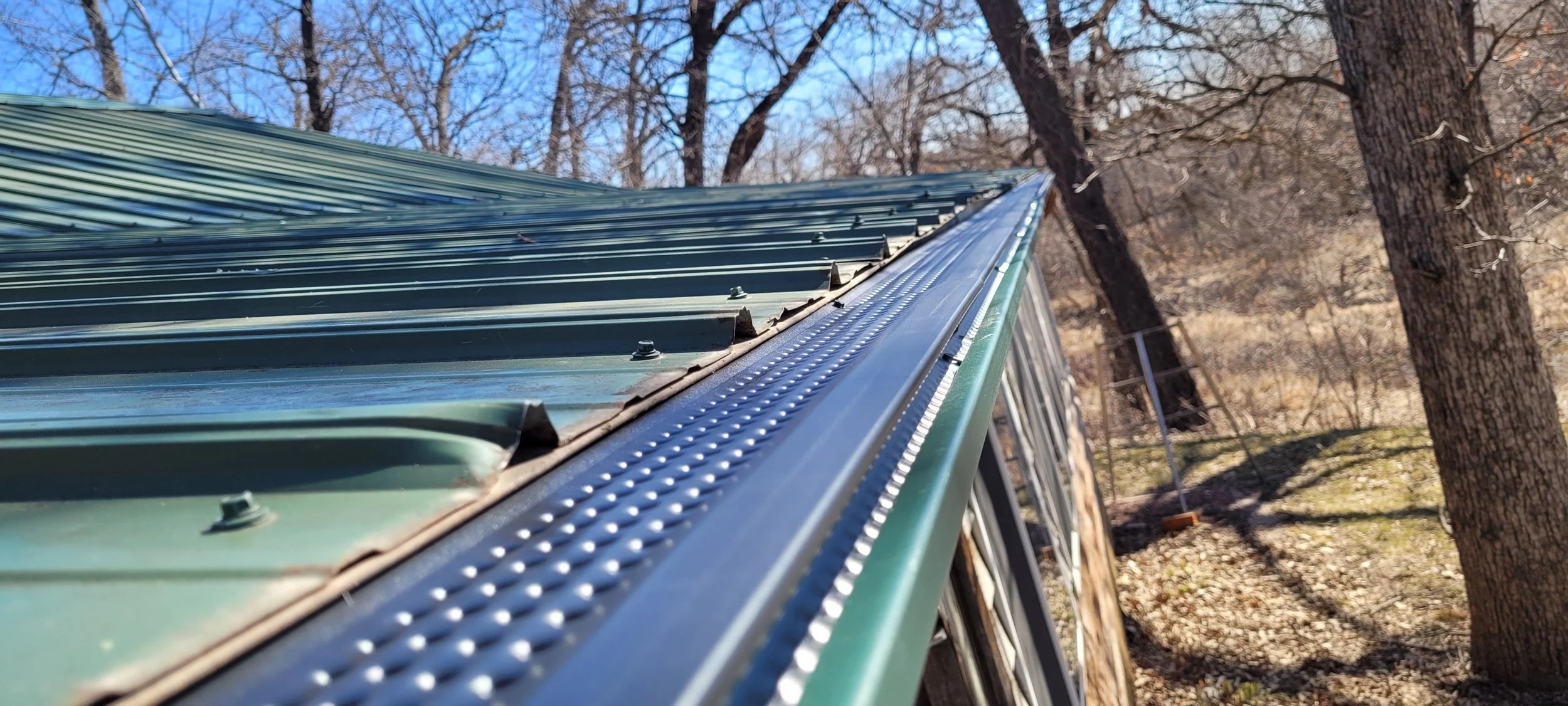 Black high flow gutter cover on a house with green metal roof