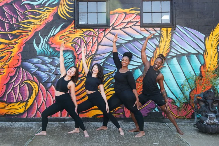 2025 teacher training cohort striking yoga poses in front of a mural