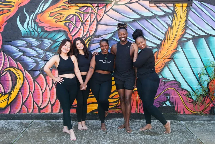 2025 yoga teacher training graduates in front of a colorful Atlanta mural