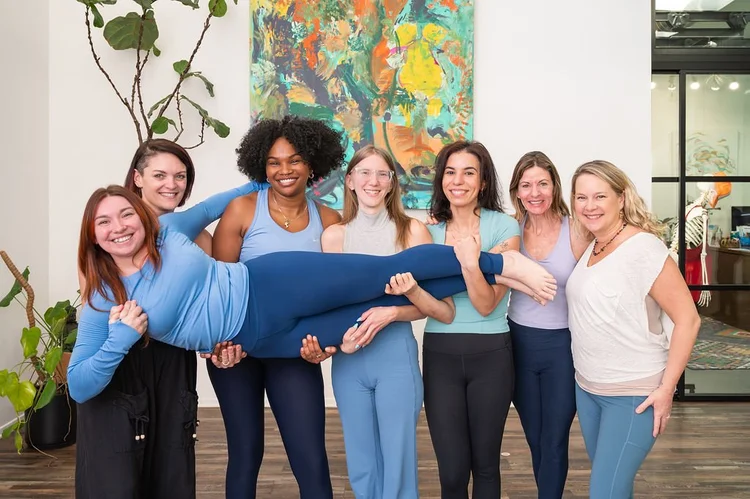 2026 Dancing Dogs Yoga teacher training cohort laughing and lifting a classmate