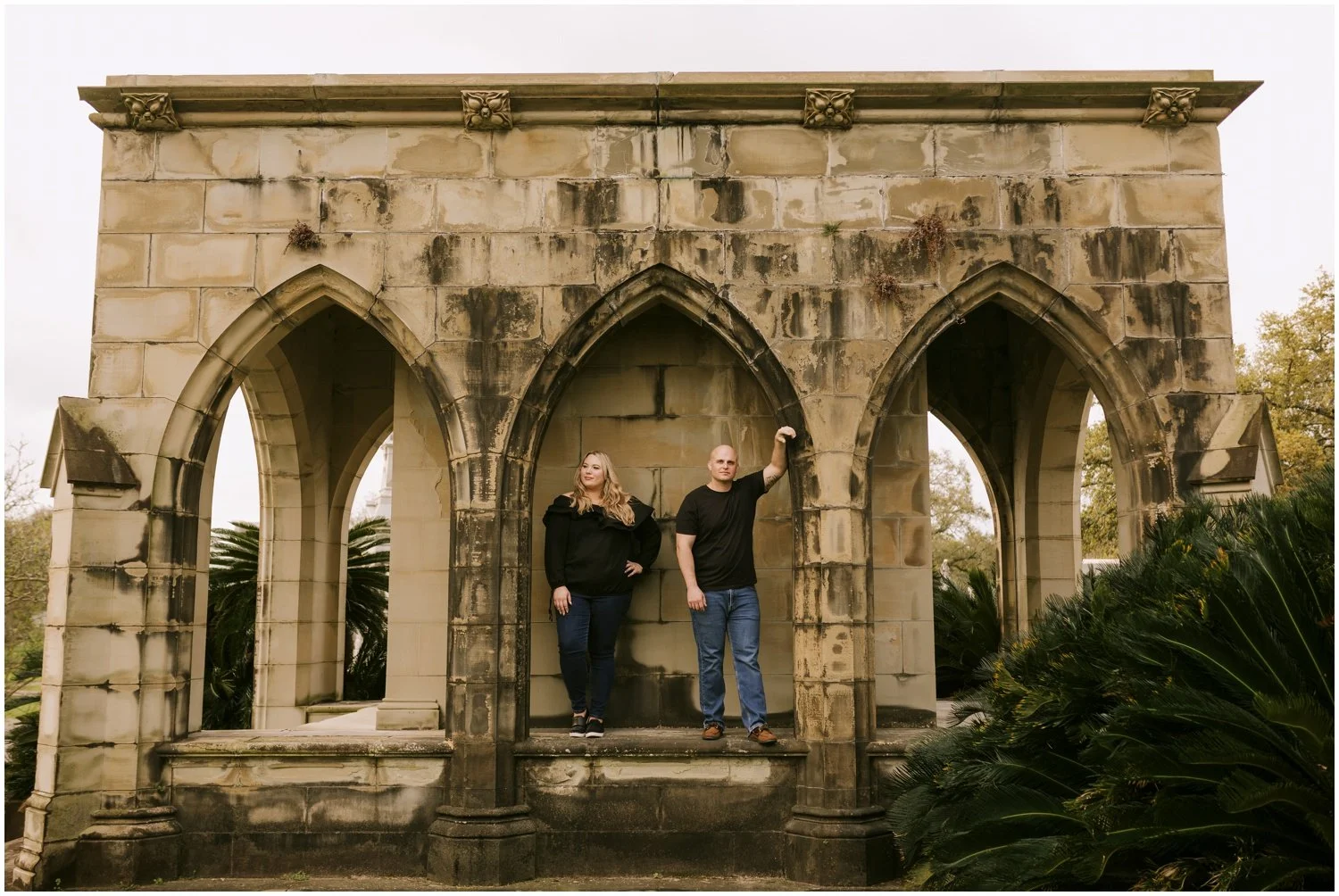 A man and woman lean against a mausoleum arch.