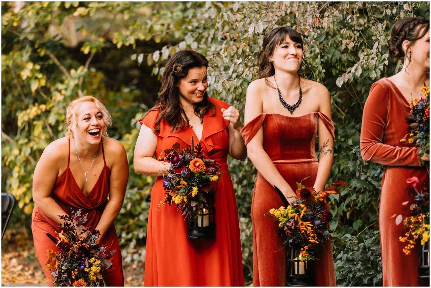 A bridesmaid in a fall bridesmaids dress doubles over in laughter.