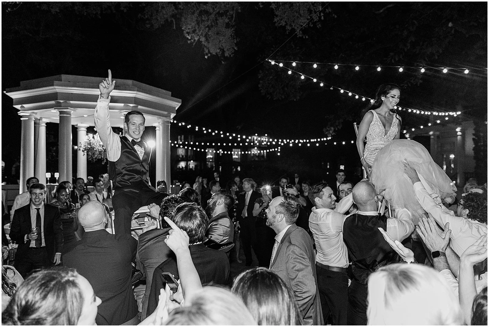 Wedding guests lift a bride and groom for the horah at a Jewish wedding reception at Elms Mansion.