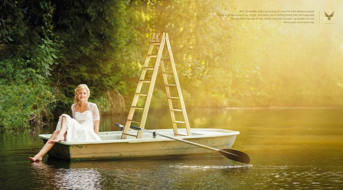A woman in a white dress sitting in a boat on a calm river, with a wooden ladder and paddle in the boat, surrounded by lush green trees and sunlight filtering through.