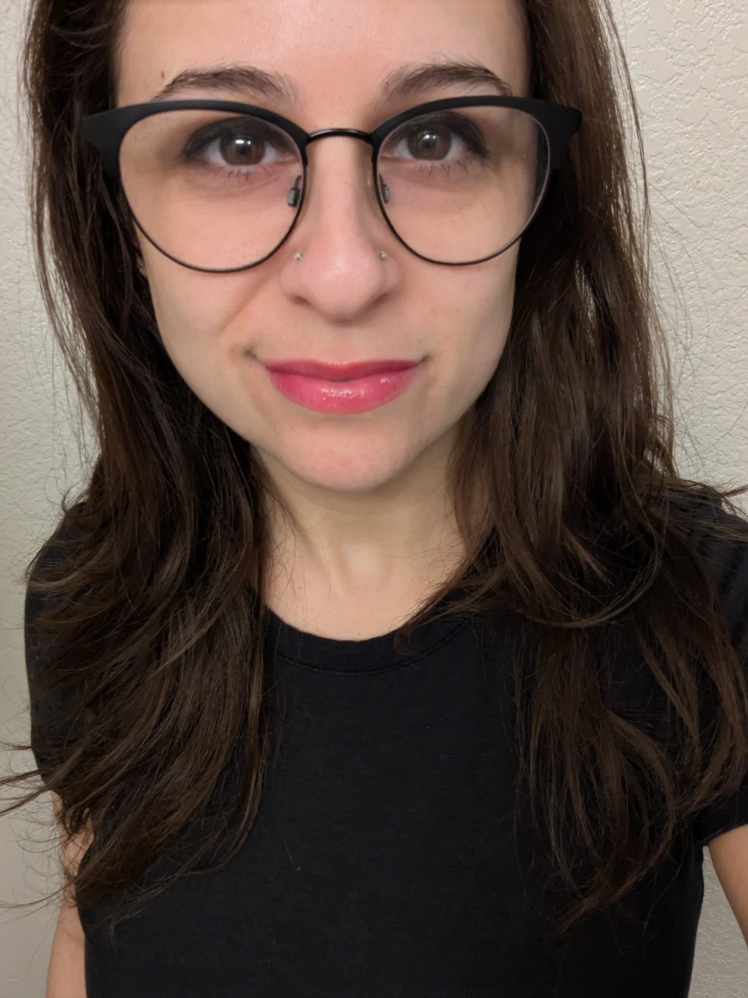 a headshot of a smiling white woman with long brown hair and a jewel stud in her nose
