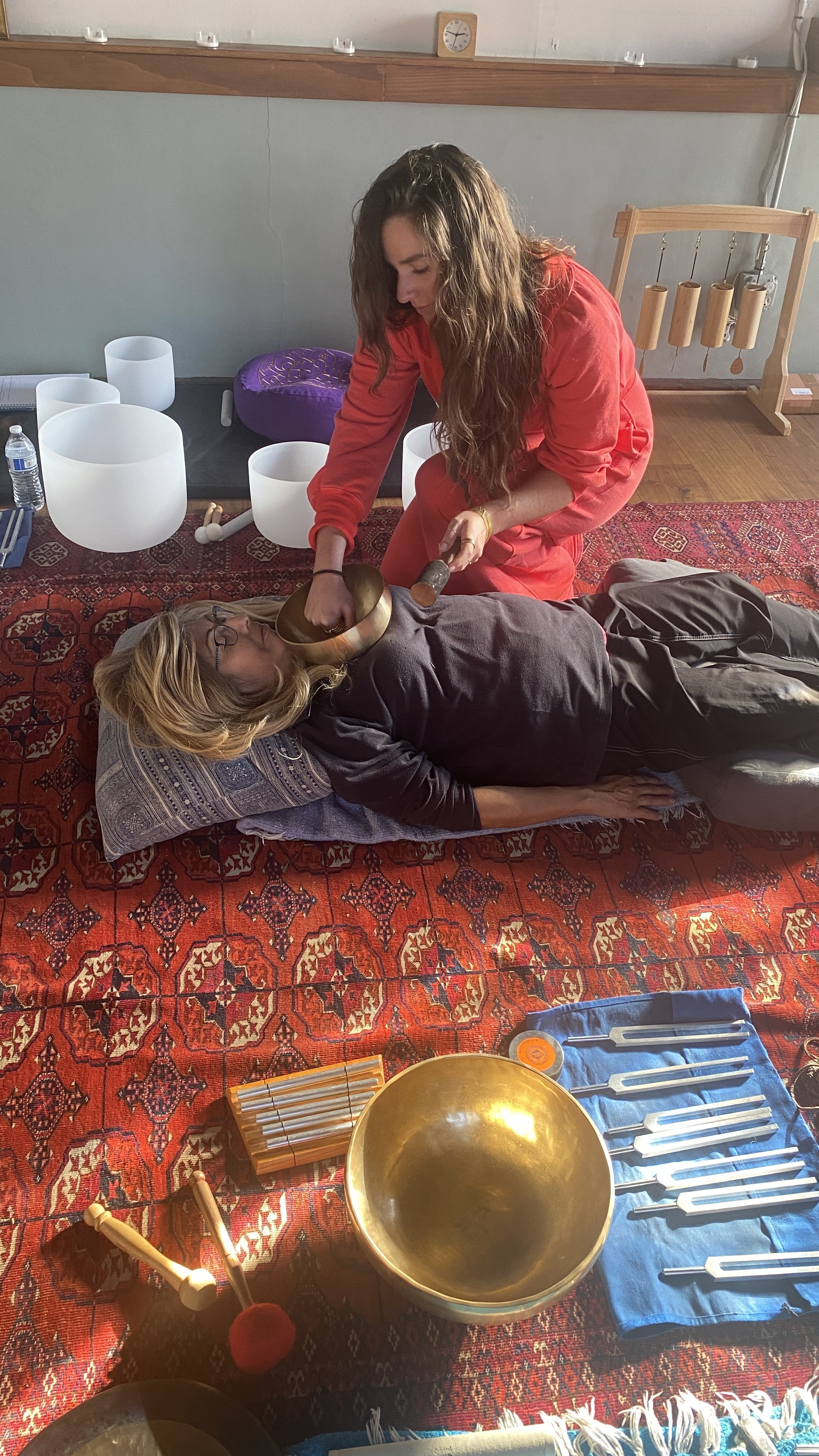 Student sound healer practicing with Tibetan bowl on another student