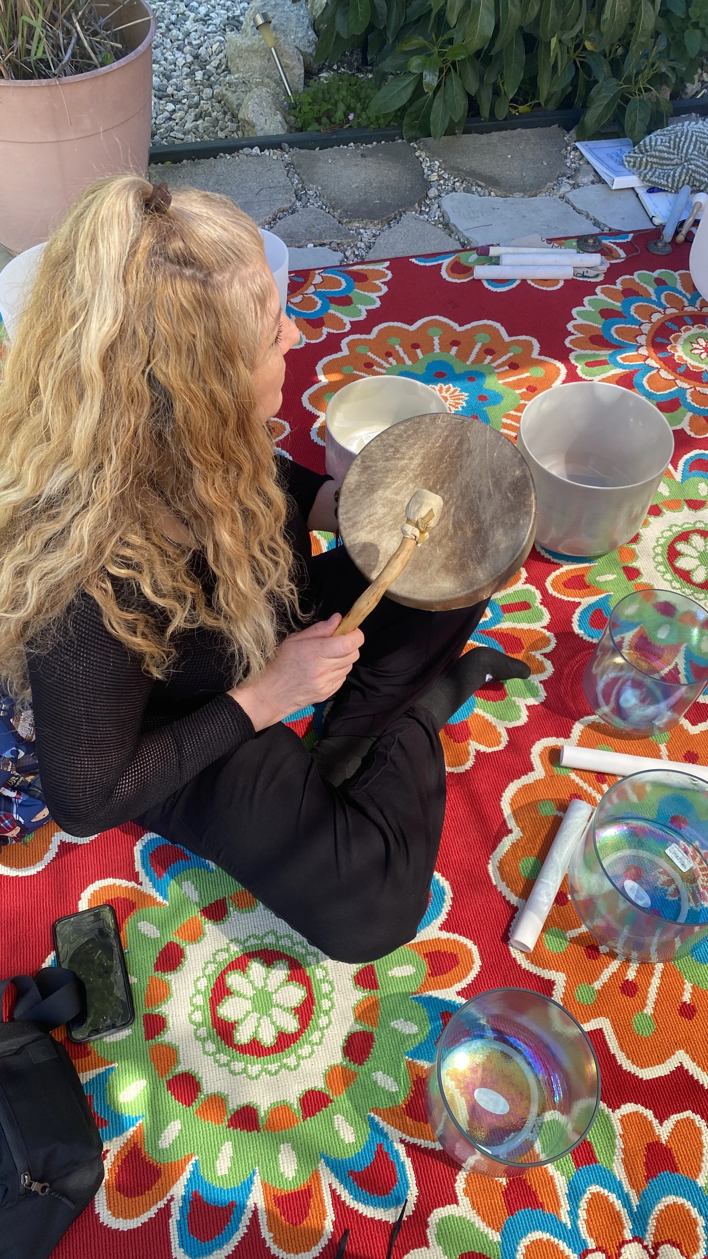 A student holding a native drum during a hands-on practice session at the Sound Healer Certification Training