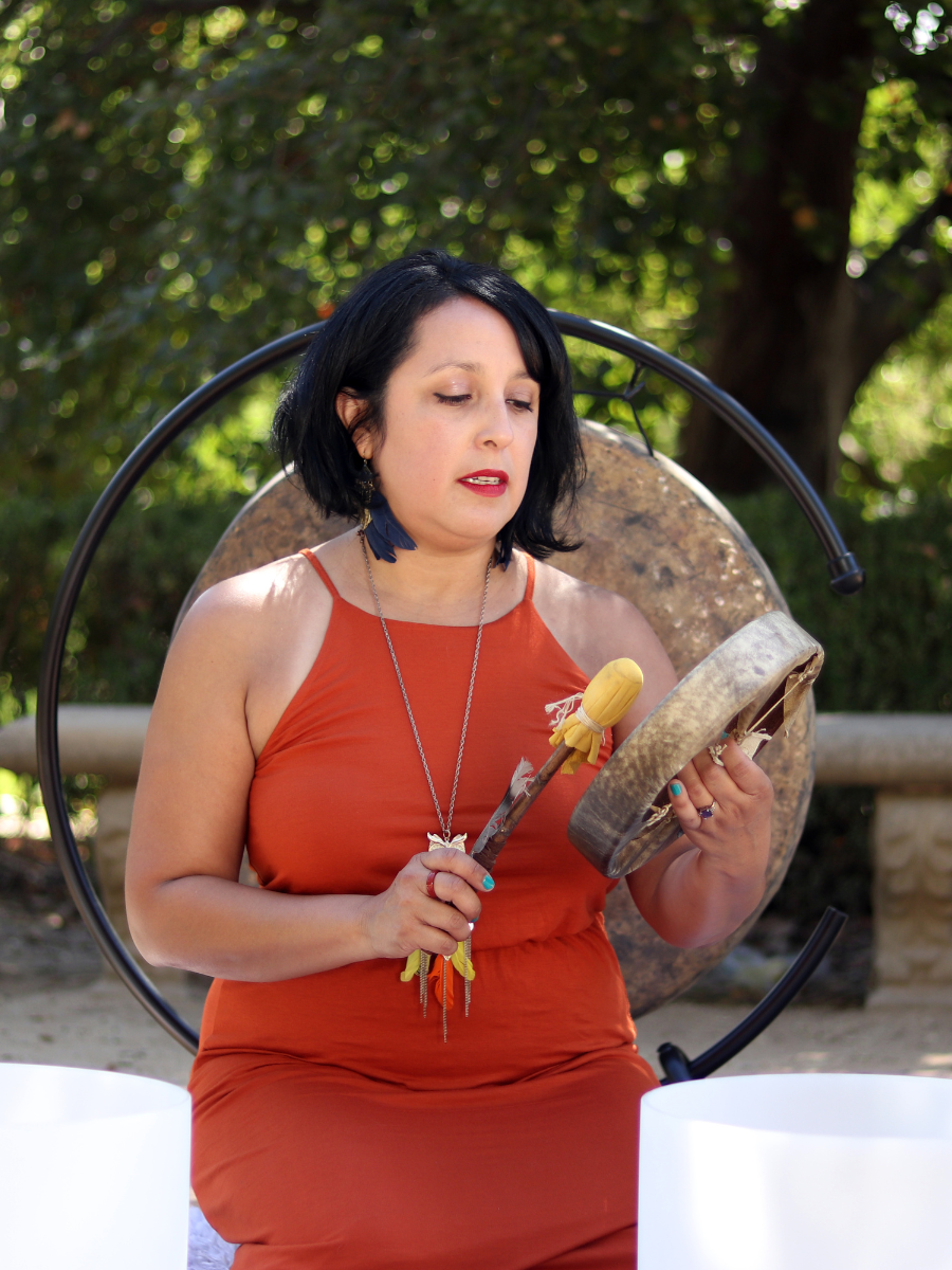 Jennifer Escalera playing a drum outdoors during a sound healing session