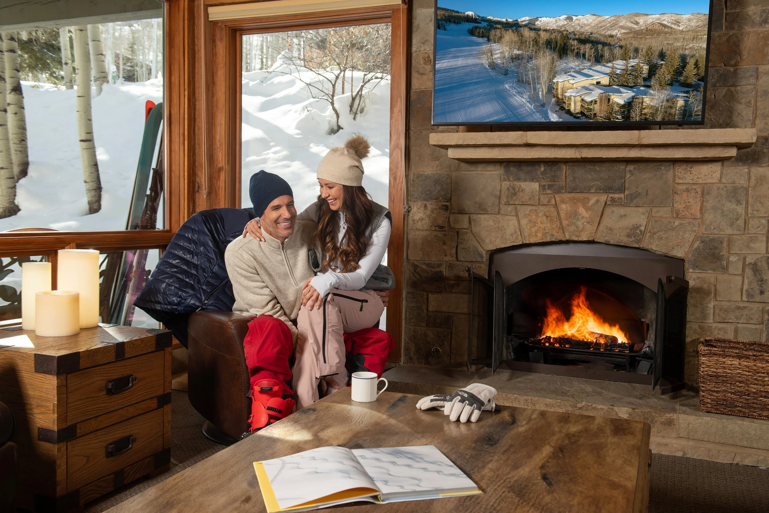 Couple relaxing by a fireplace inside a winter mountain resort, photographed for seasonal hospitality marketing and campaign storytelling.