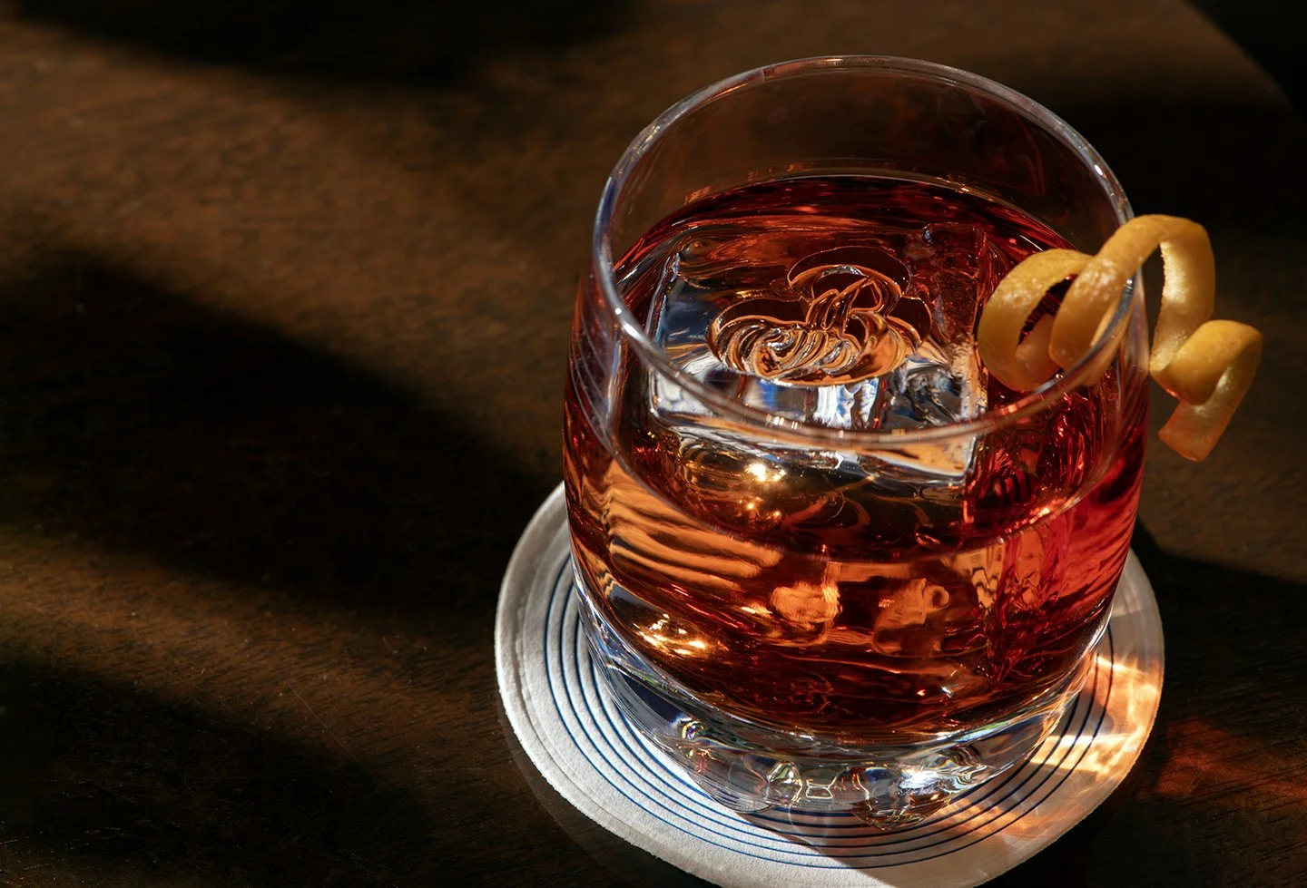 Close-up of a Negroni cocktail with orange twist in dramatic light, photographed by Chad Chisholm Creative for food and beverage branding.