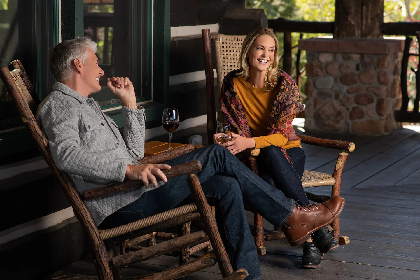 Couple relaxing on a rustic lodge porch with glasses of wine, photographed by Chad Chisholm Creative to capture authentic guest experience and connection.