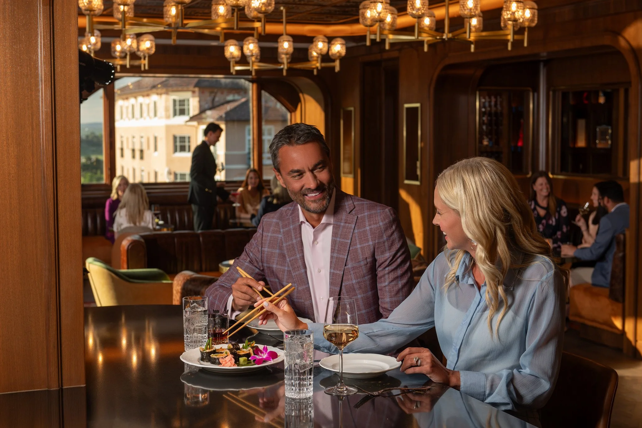 Couple enjoying sushi and drinks in an upscale hotel restaurant showcasing luxury hospitality photography and authentic guest experience.