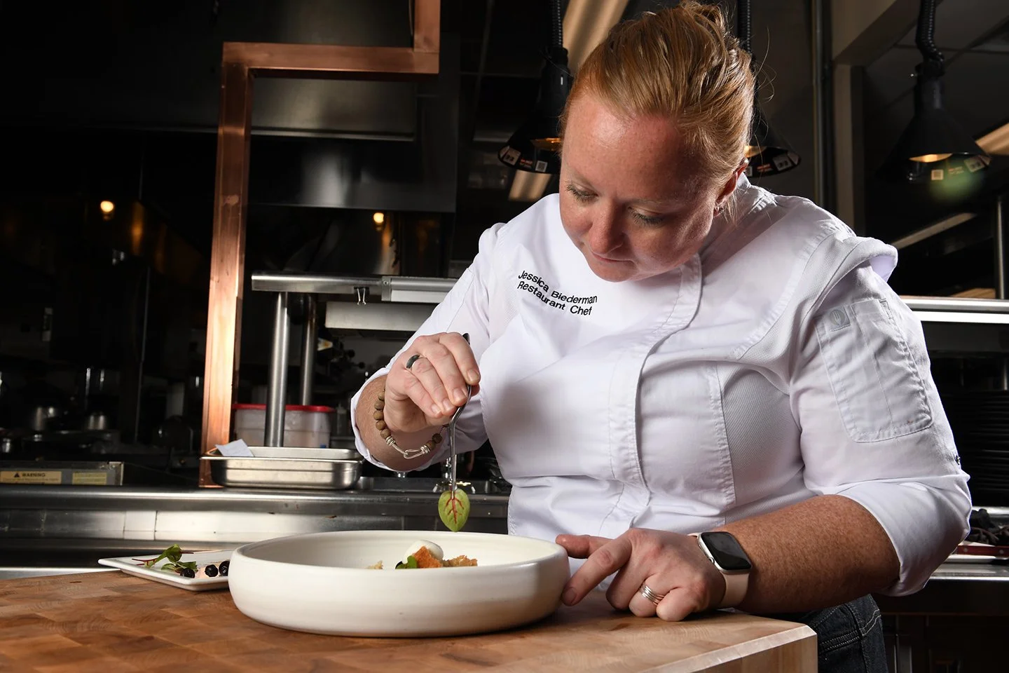 Professional chef plating a dish in a restaurant kitchen, photographed by Chad Chisholm Creative to highlight craftsmanship and editorial brand storytelling.