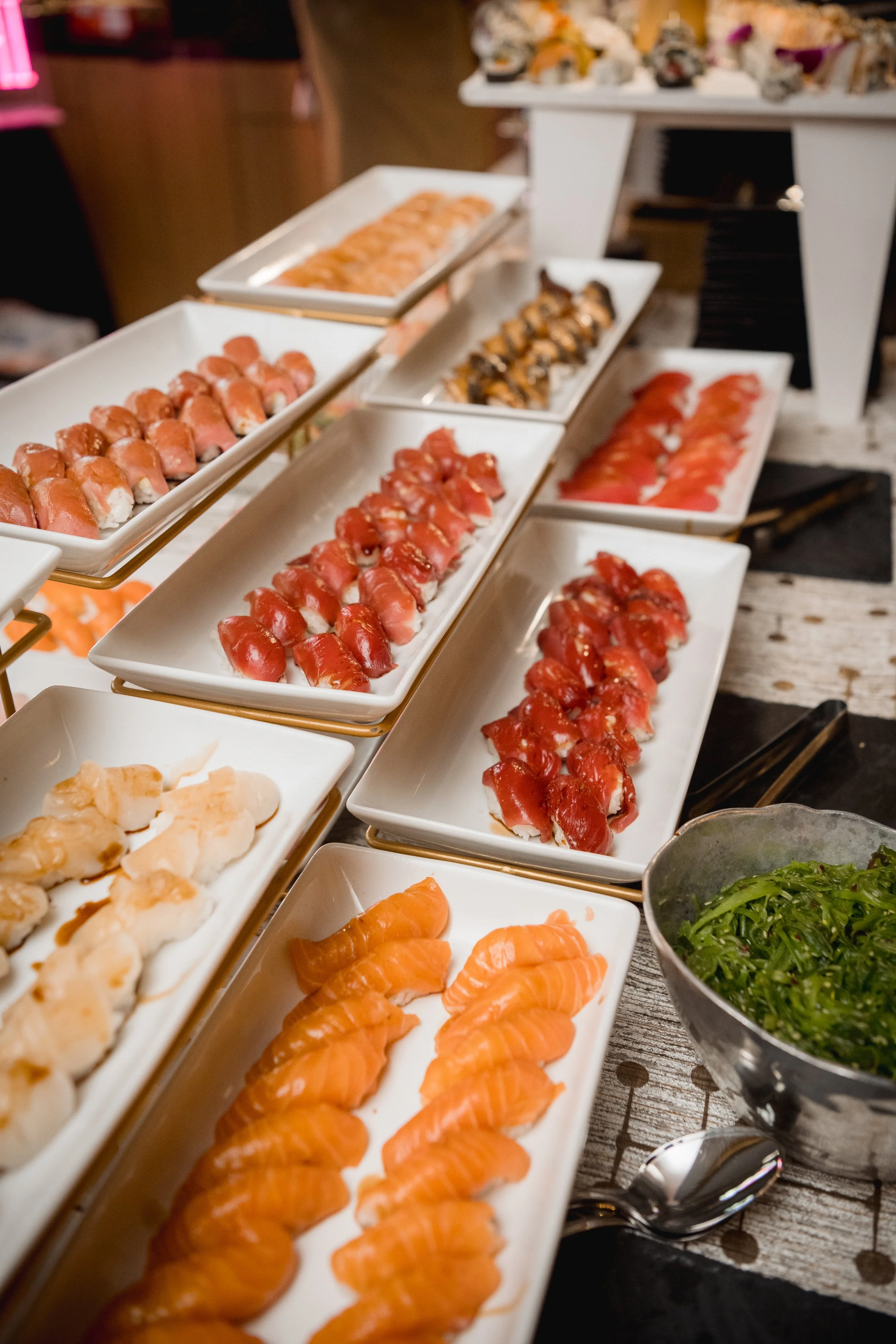 Trays of sliced tuna and salmon sashimi laid out for catering