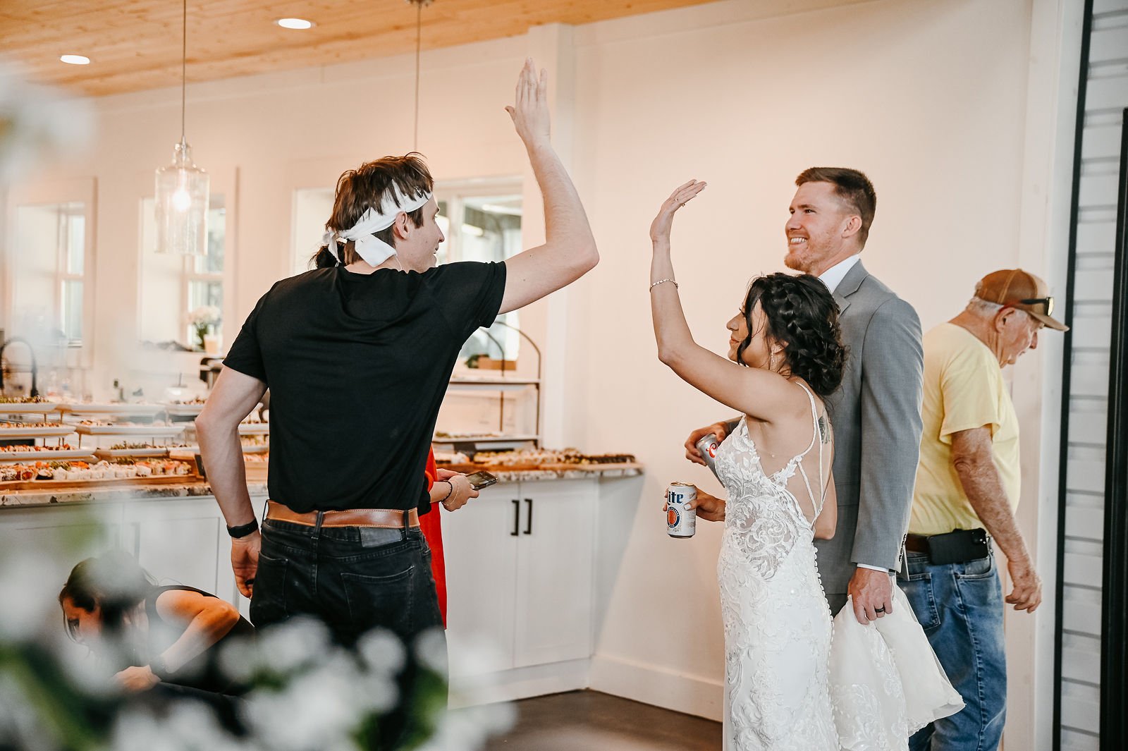 A bride and groom celebrating with a high-five while a LAV Sushi chef prepares food at their wedding reception