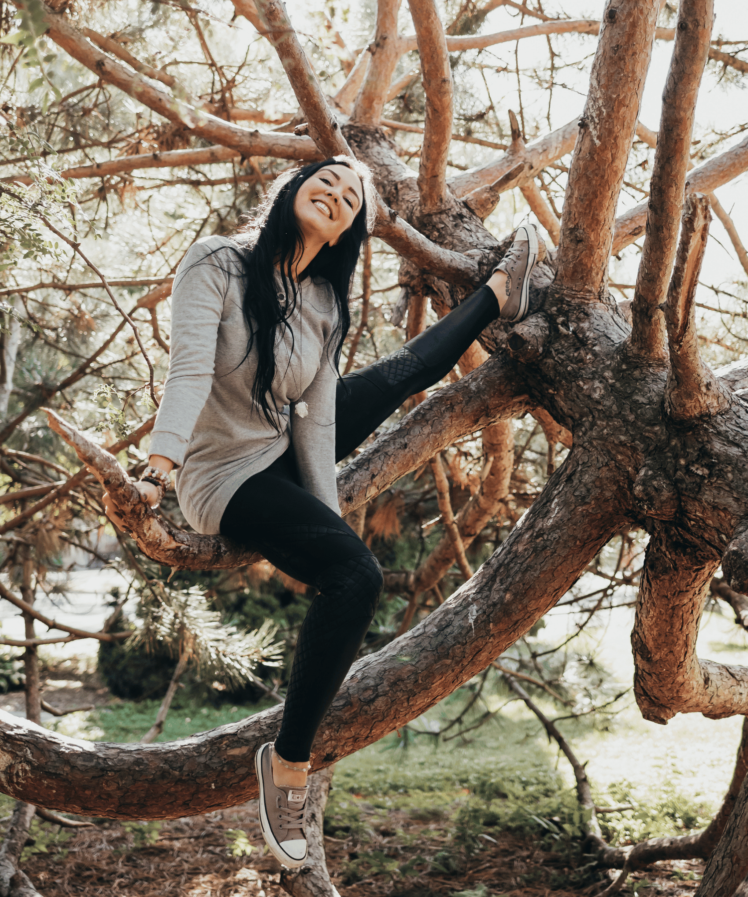 Chivonne Monaghan in a tree, grounded in nature and joy, representing healing, resilience, and personal transformation.