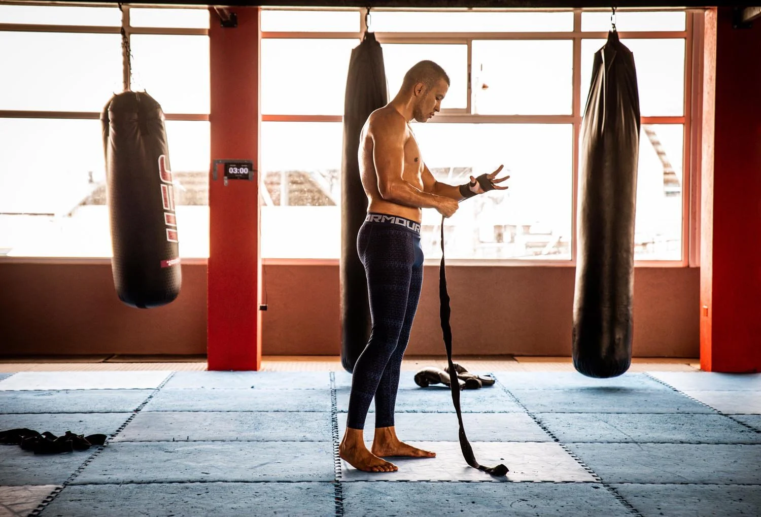 Man wrapping hands in a gym with punching bags.