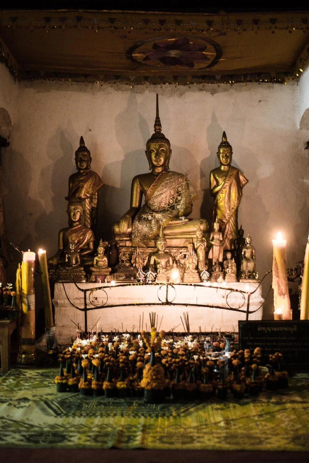 Buddha statues in a shrine with candles and incense offerings