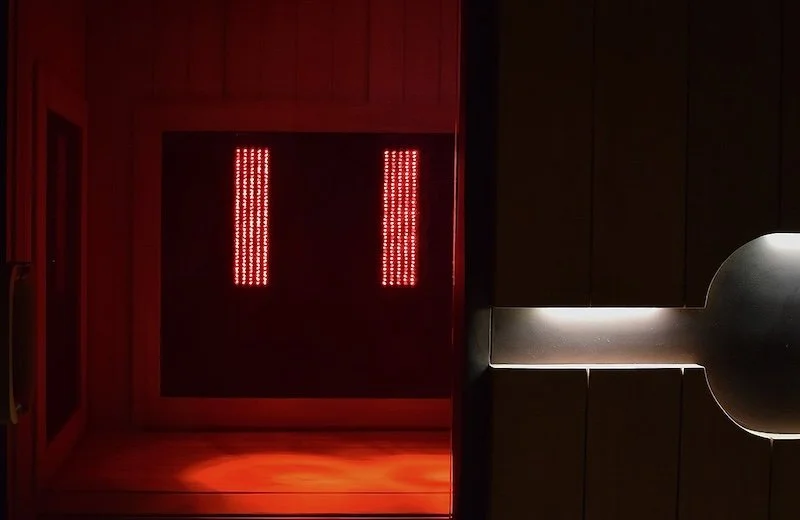 Infrared sauna interior with red lights and a wooden door.