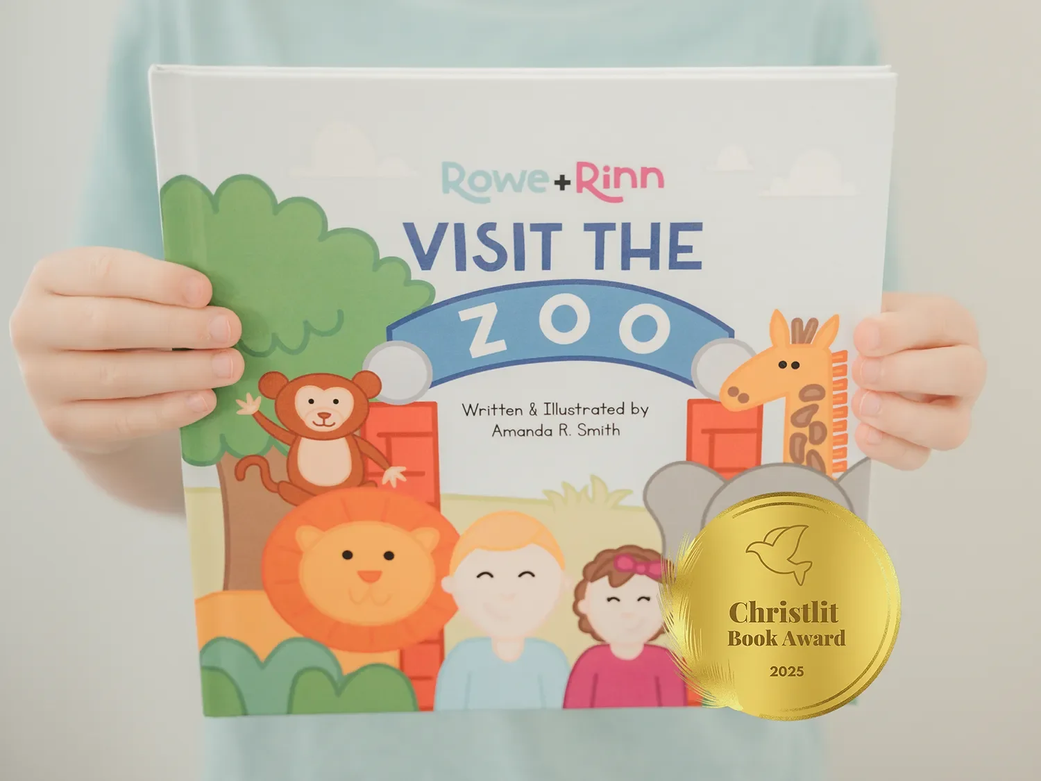 Child holding a children's book titled "Visit the Zoo" by Amanda R. Smith, featuring illustrations of animals and cartoon characters.