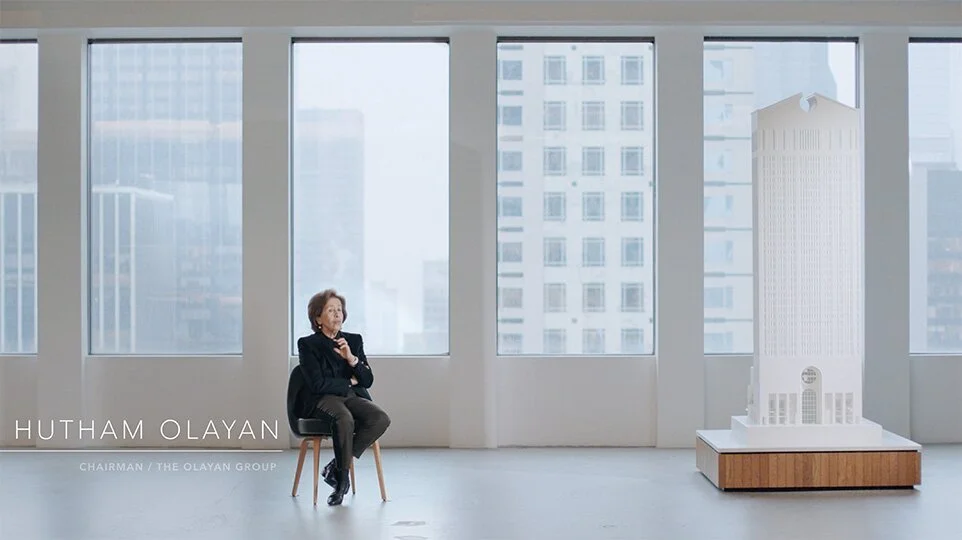 Hutham Olayan, Chairman, The Olayan Group, sits for an interview beside a white scale model of 550 Madison, city towers behind her.