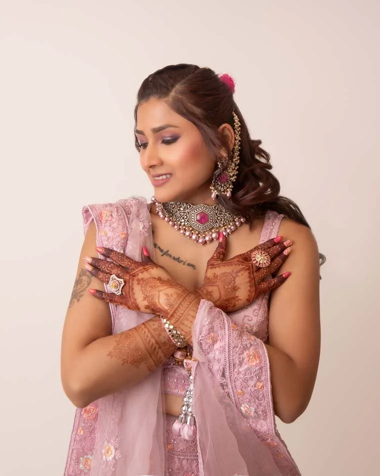 Woman dressed in traditional South Asian, Indian attire, adorned with intricate jewelry and henna, crossing her hands gracefully. Elegant and cultural portrait photography in Lancaster, PA