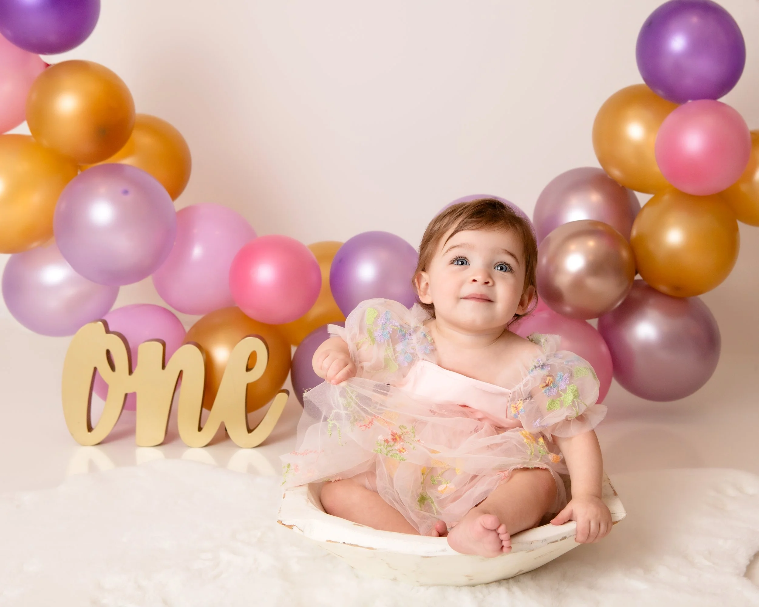 littel girl dressed in pink with colorful balloons