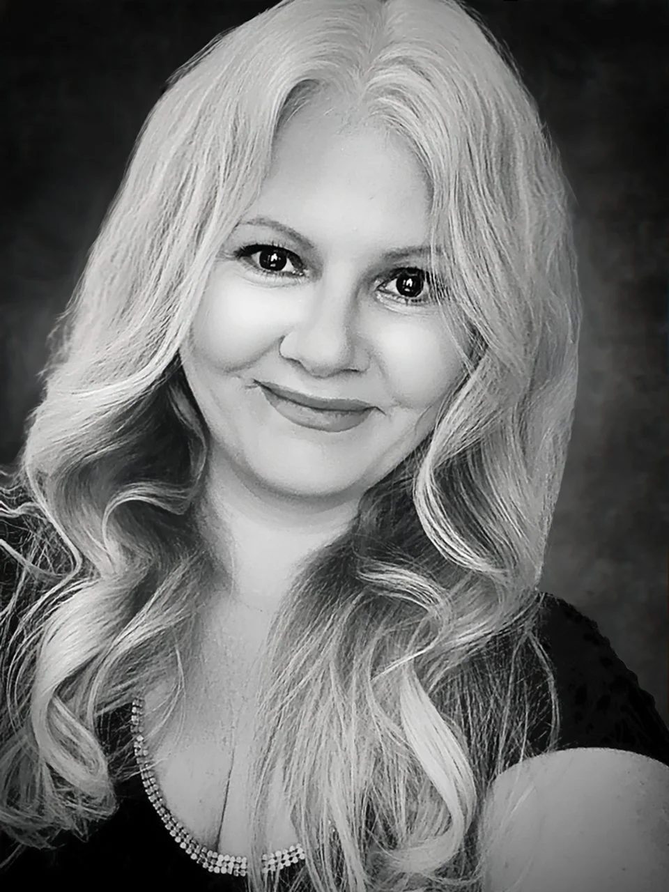 Katleen Dicomo - Black and white portrait of a Kat Dicomo with long, wavy blonde hair, wearing a black top with a decorative neckline.