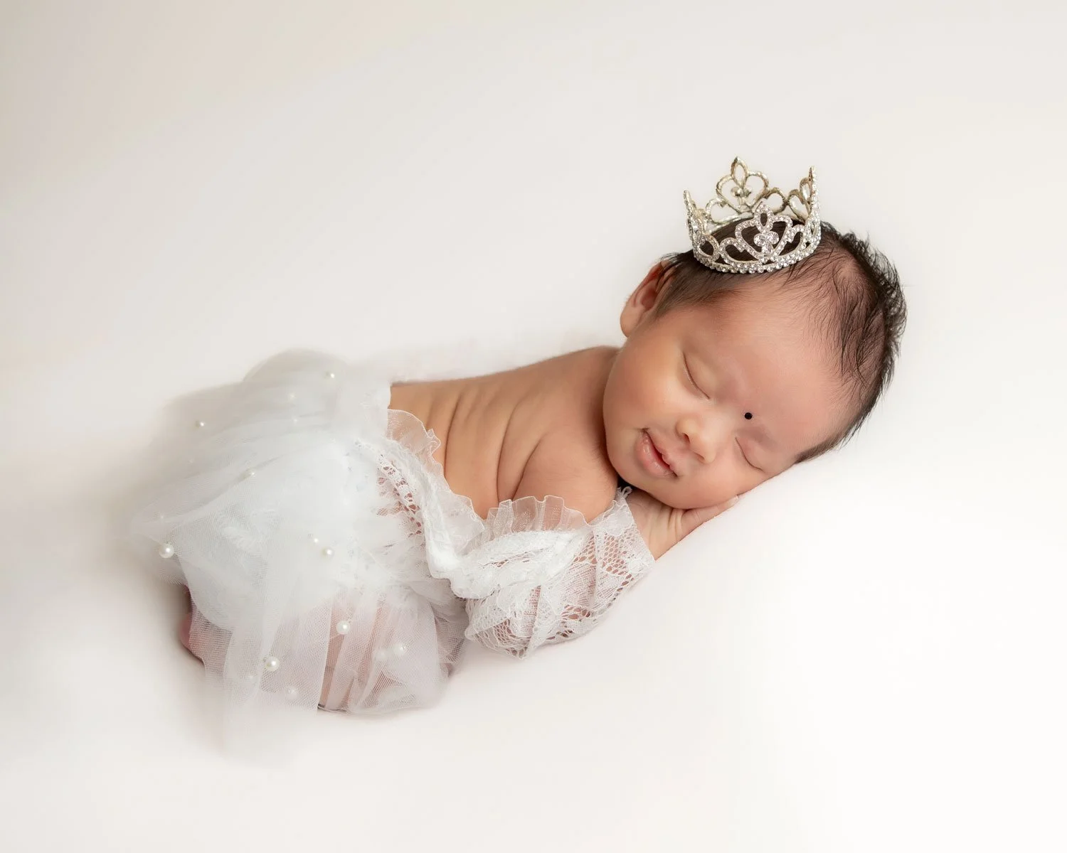 Newborn baby sleeping with a tiara. Tender and dreamy newborn photography in Lancaster, PA.