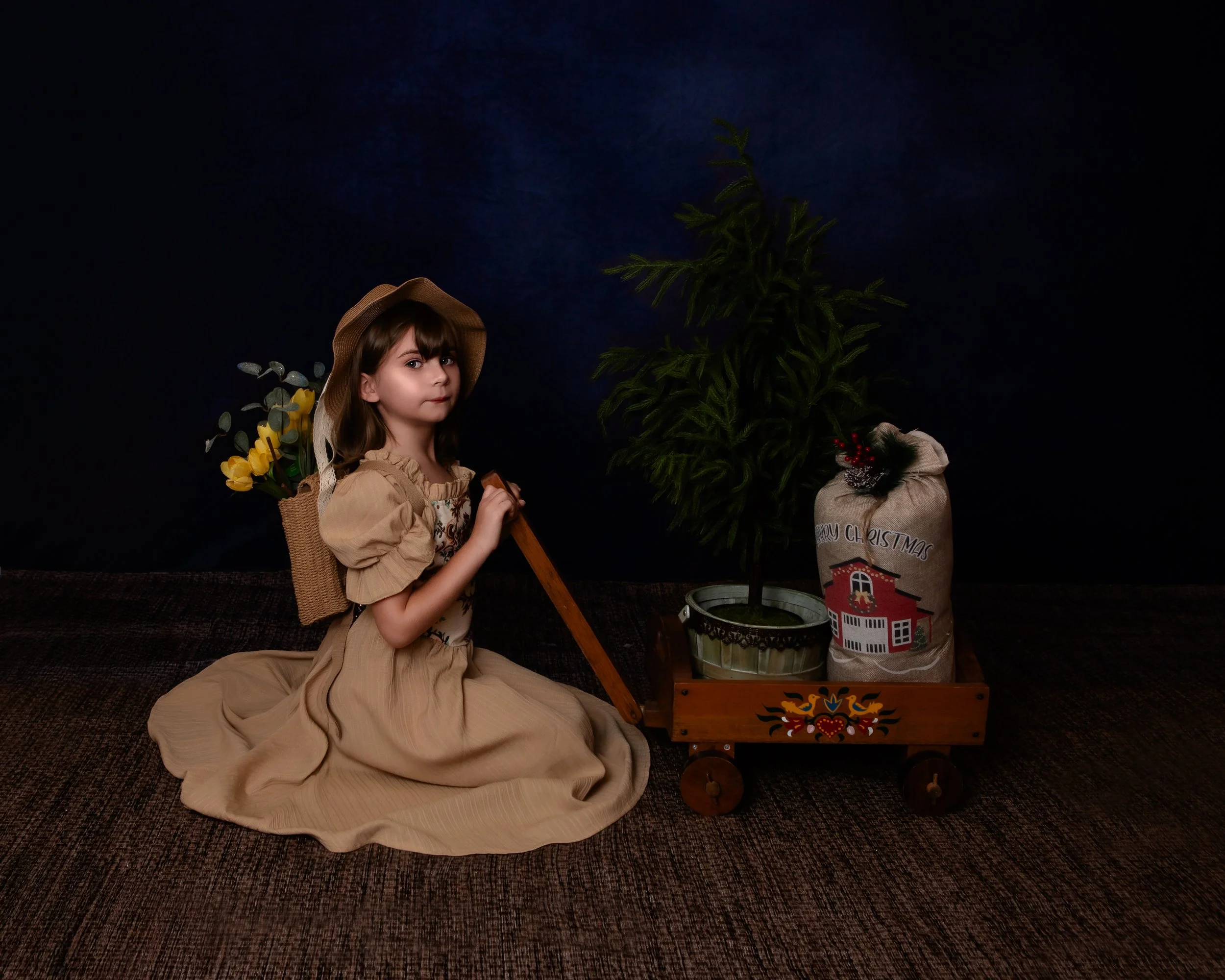 a little girl with a backback filled with flowers holidng the handle of a wagon