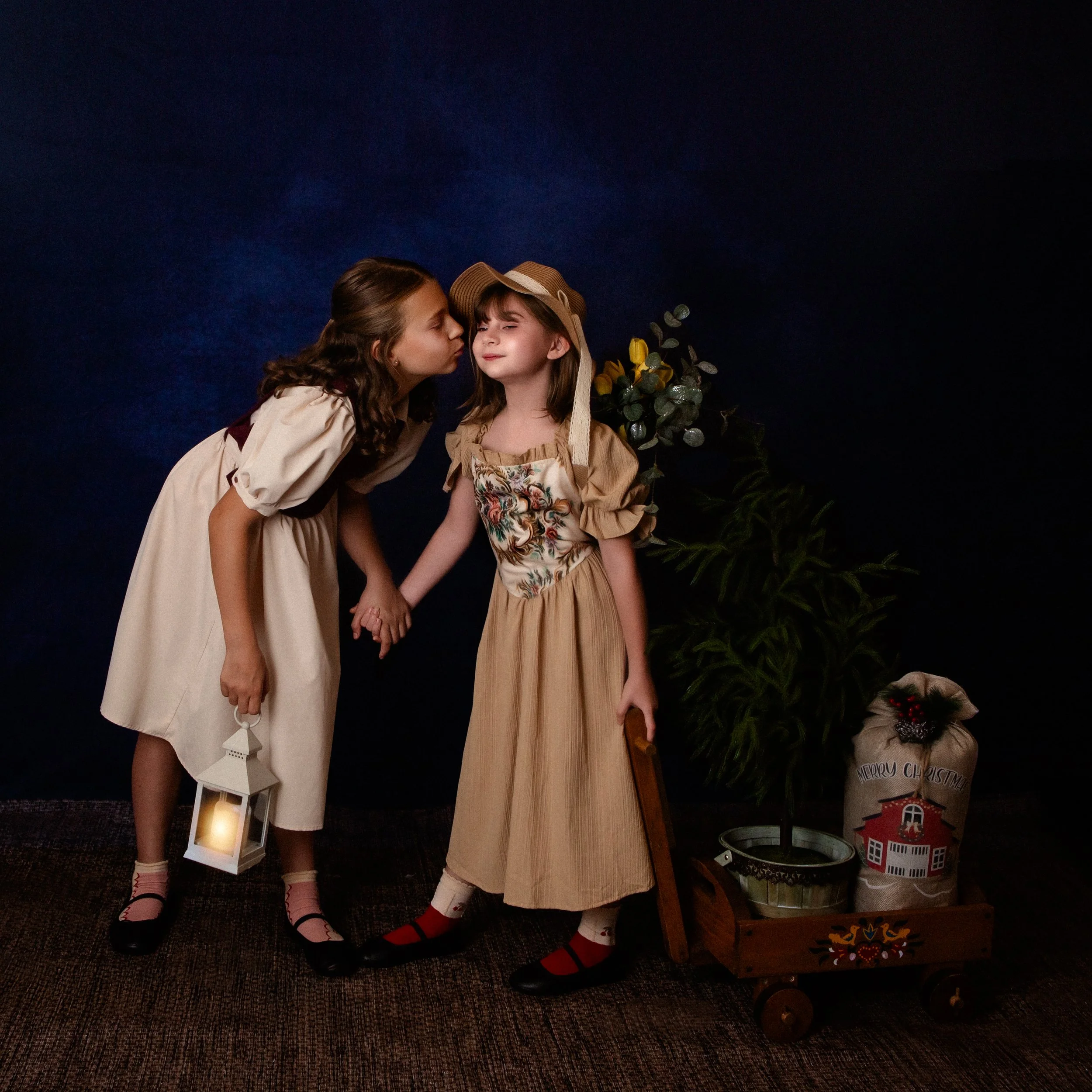 two girls with the older one kissing the little girl on the cheek