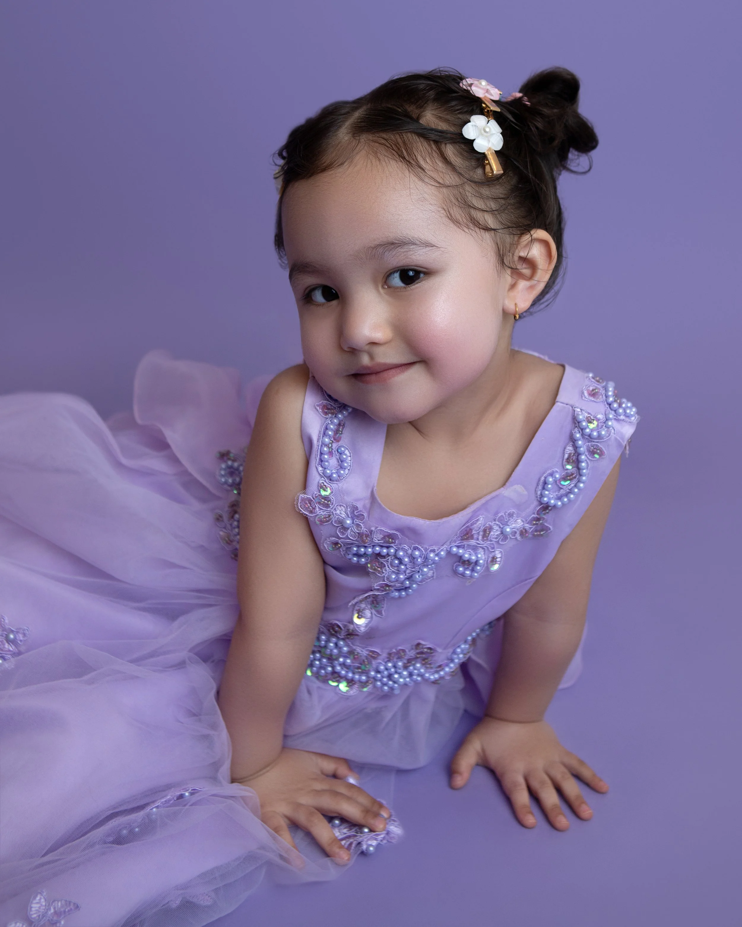 3 year old girl wearing a purple sparkle dress with a matching purple background