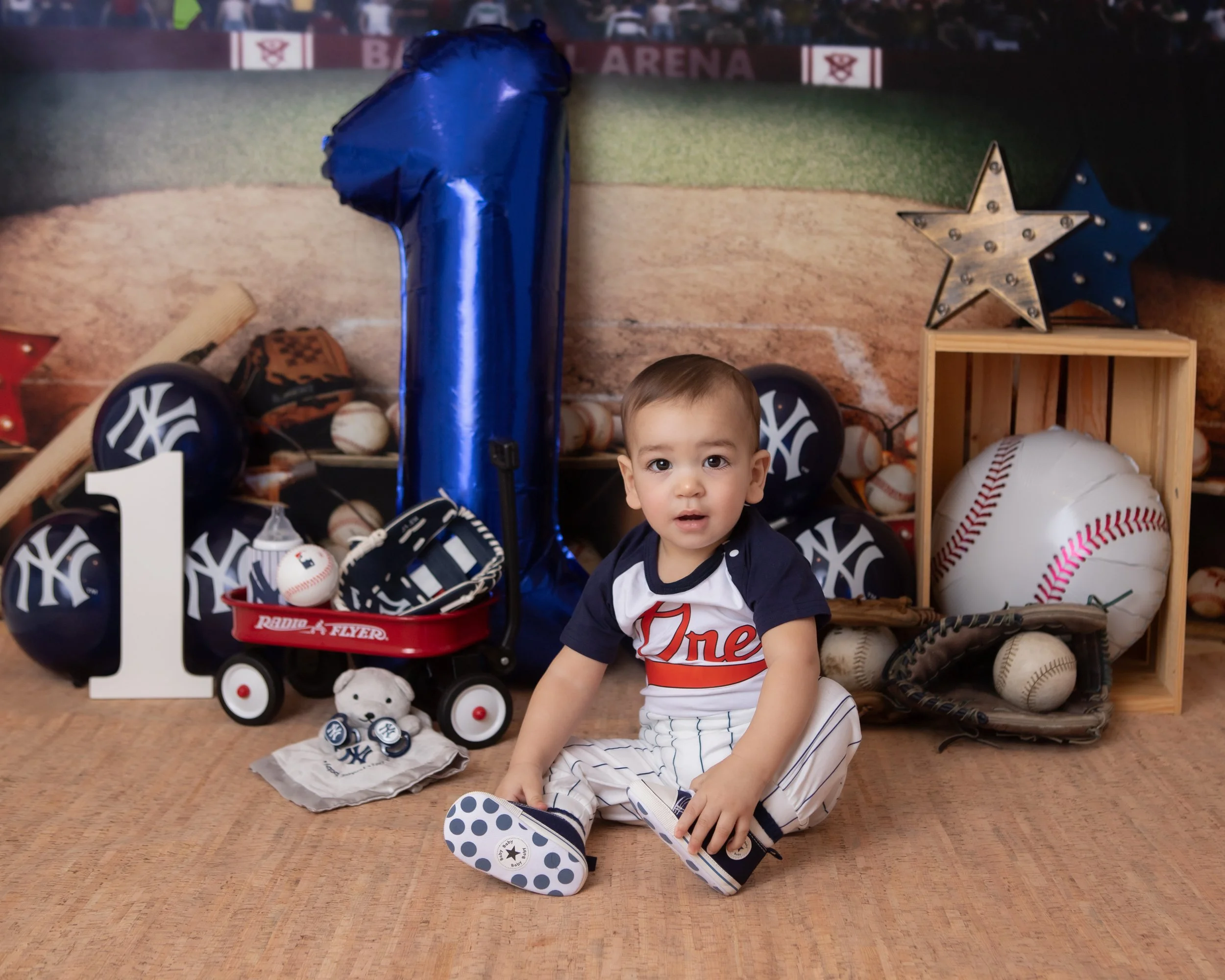 one year old boy wearing a baseball uniform with the yankee baseball feild 