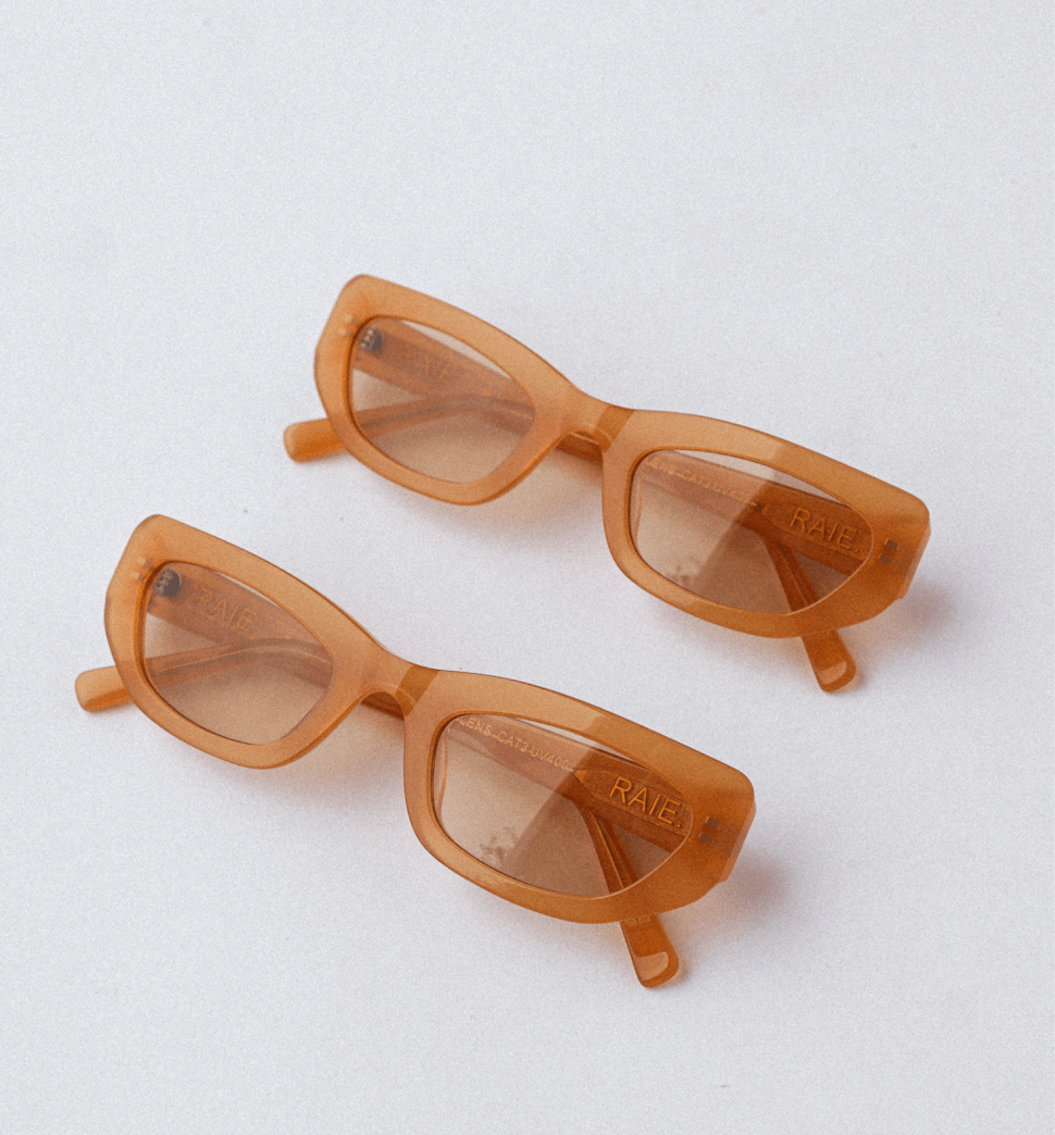 Two pairs of orange, rectangular sunglasses with slightly curved corners and tinted lenses, positioned on a white surface.