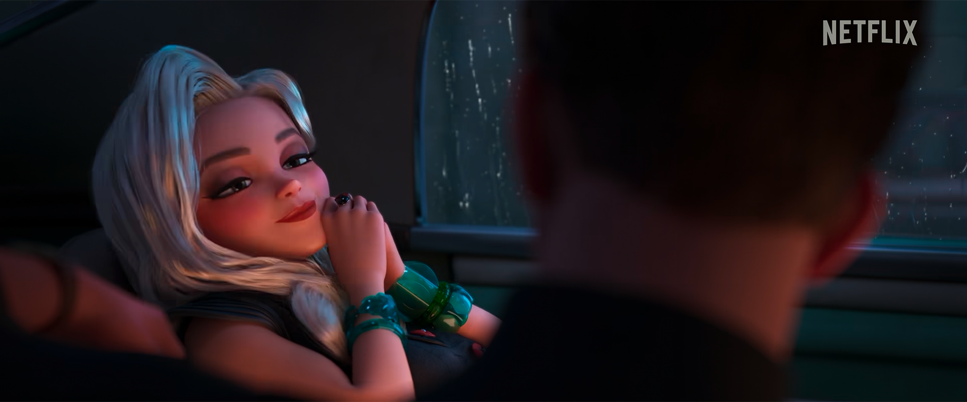 Animated woman with blonde hair and makeup, wearing multiple green bracelets, sitting in a car, gazing fondly at someone out of frame with a rainy window in the background.