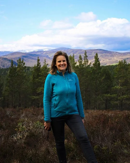 Professional Scottish tour guide Nicola Fraser standing amongst the scenic mountain landscapes of the Highlands