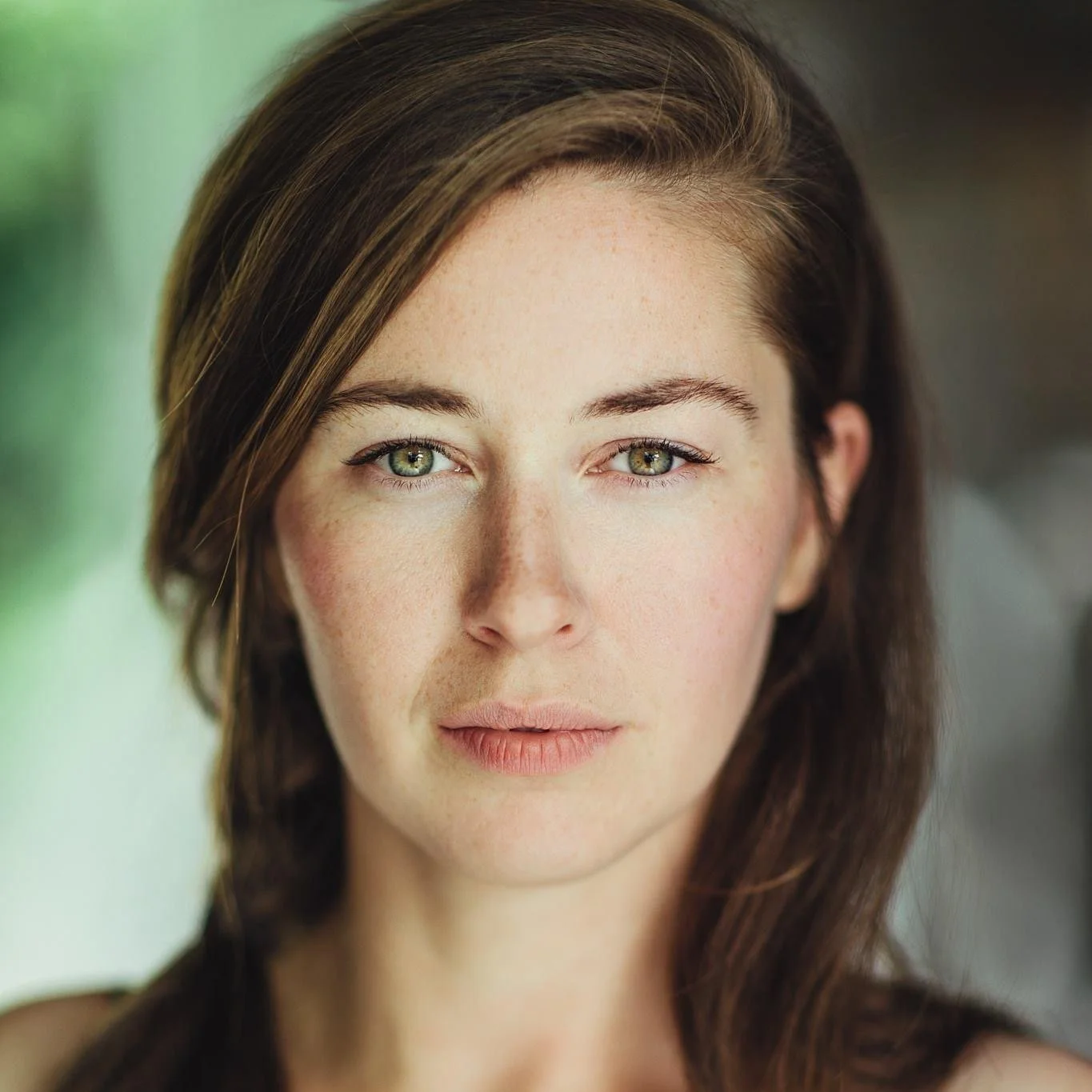 Close-up portrait of a woman with fair skin, green eyes, and brown hair.