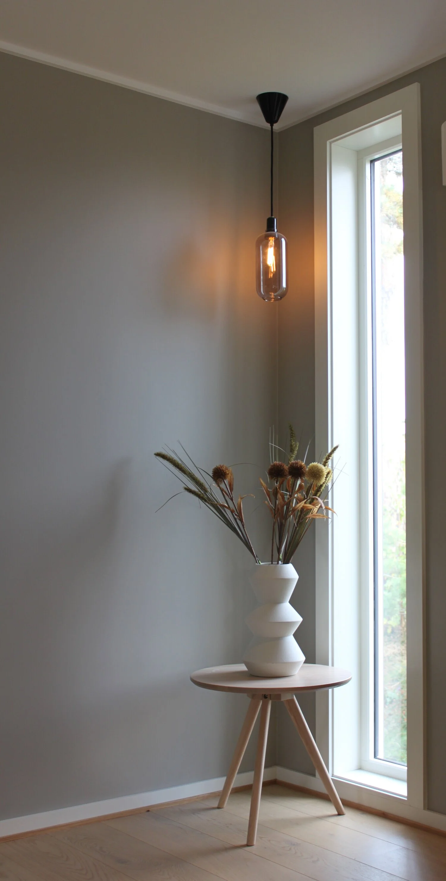 Det ble satt inn et nytt vindu fra gulv til tak for å gi et mørkt hjørne lys og liv. Vinduet er en egen detalj i boligen som harmonerer med spilenes stramme og rette form.