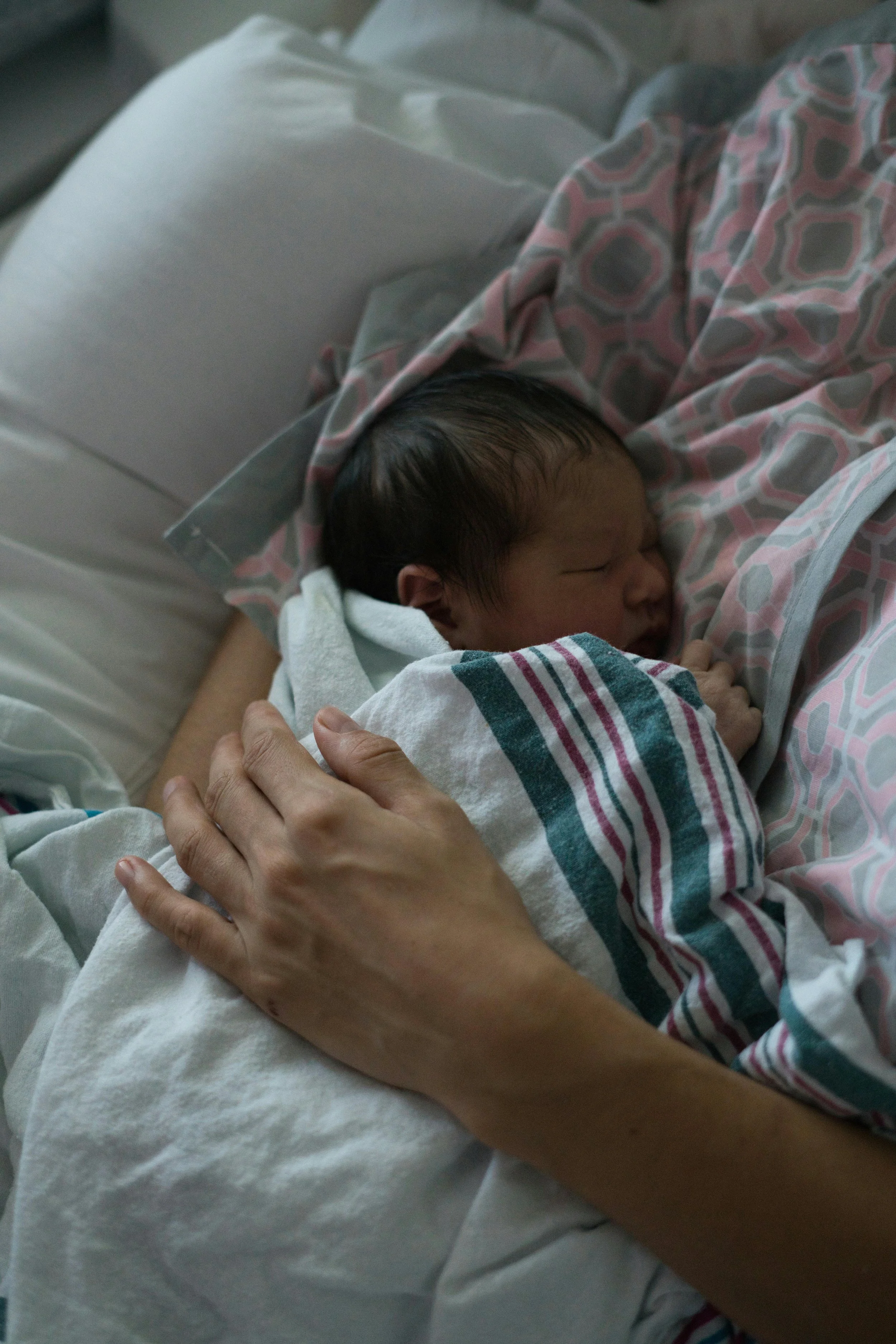 Newborn baby wrapped in blanket cradled by mother