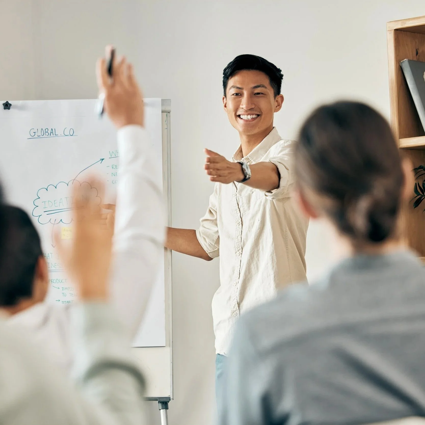 A young man is giving a presentation to a group of people in an office or classroom.
