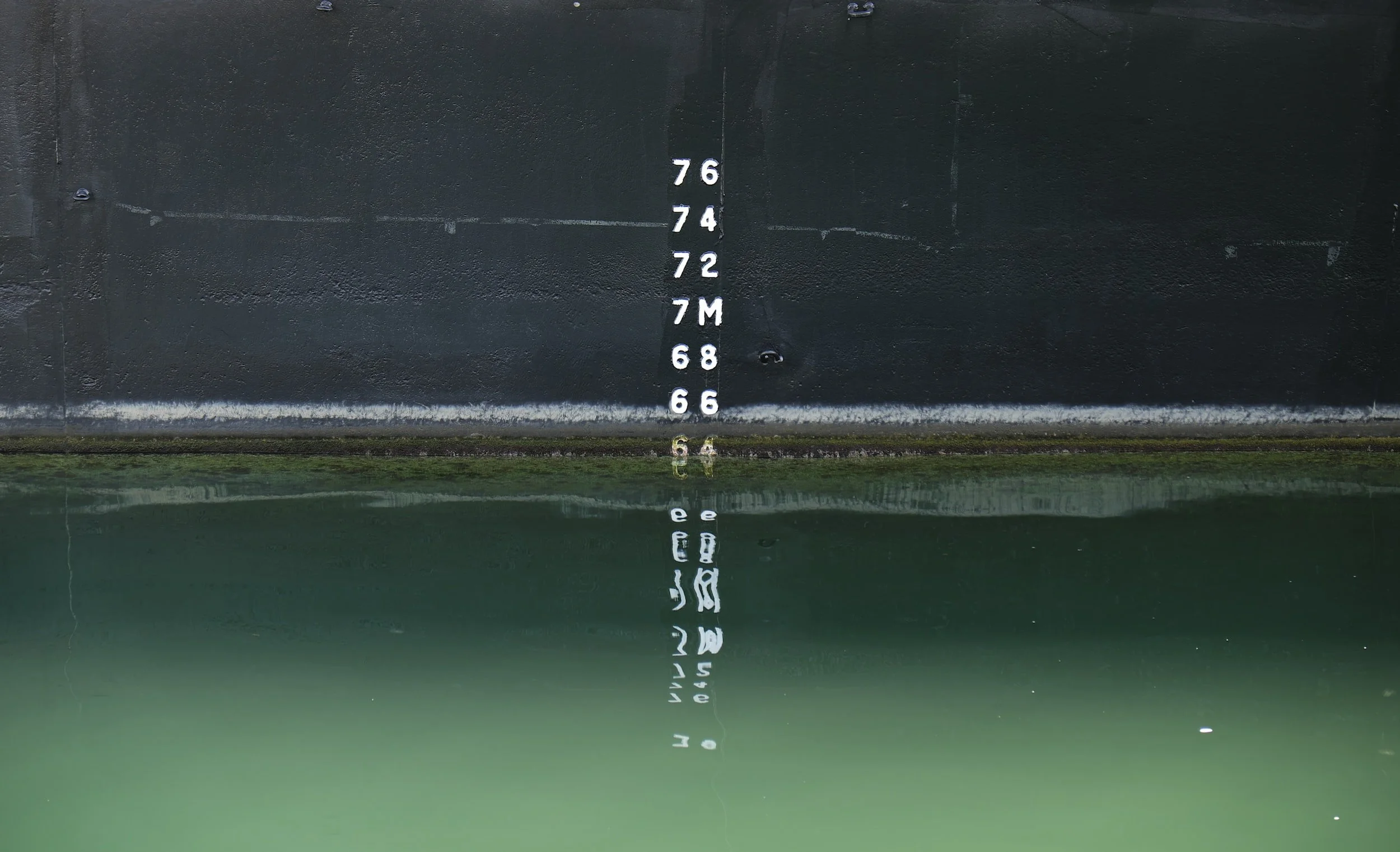 Ship's waterline height measurement chart with numbers and letters reflected in the water.