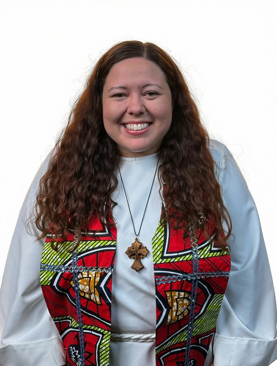 Person in clerical collar and black shirt with long sleeves, smiling.