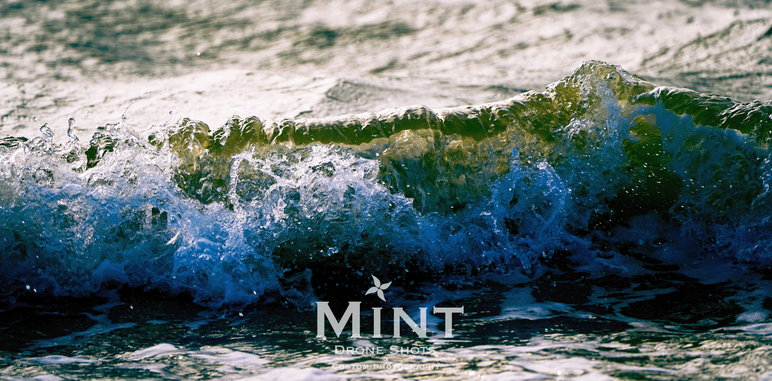 Close-up of an ocean wave crashing with white foam and green water, captured in dynamic motion.