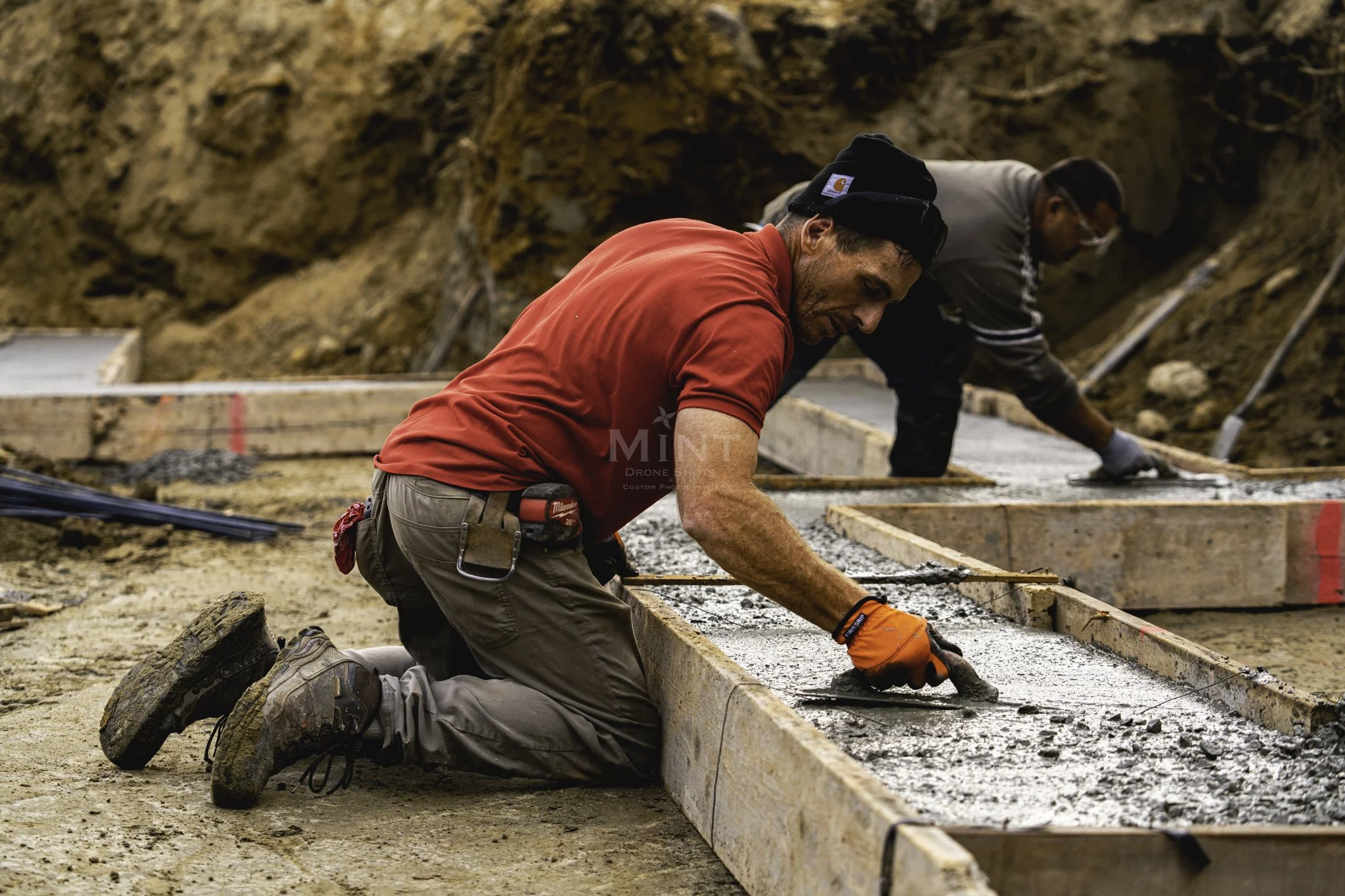 Construction worker smoothing wet concrete in wooden frame at construction site.