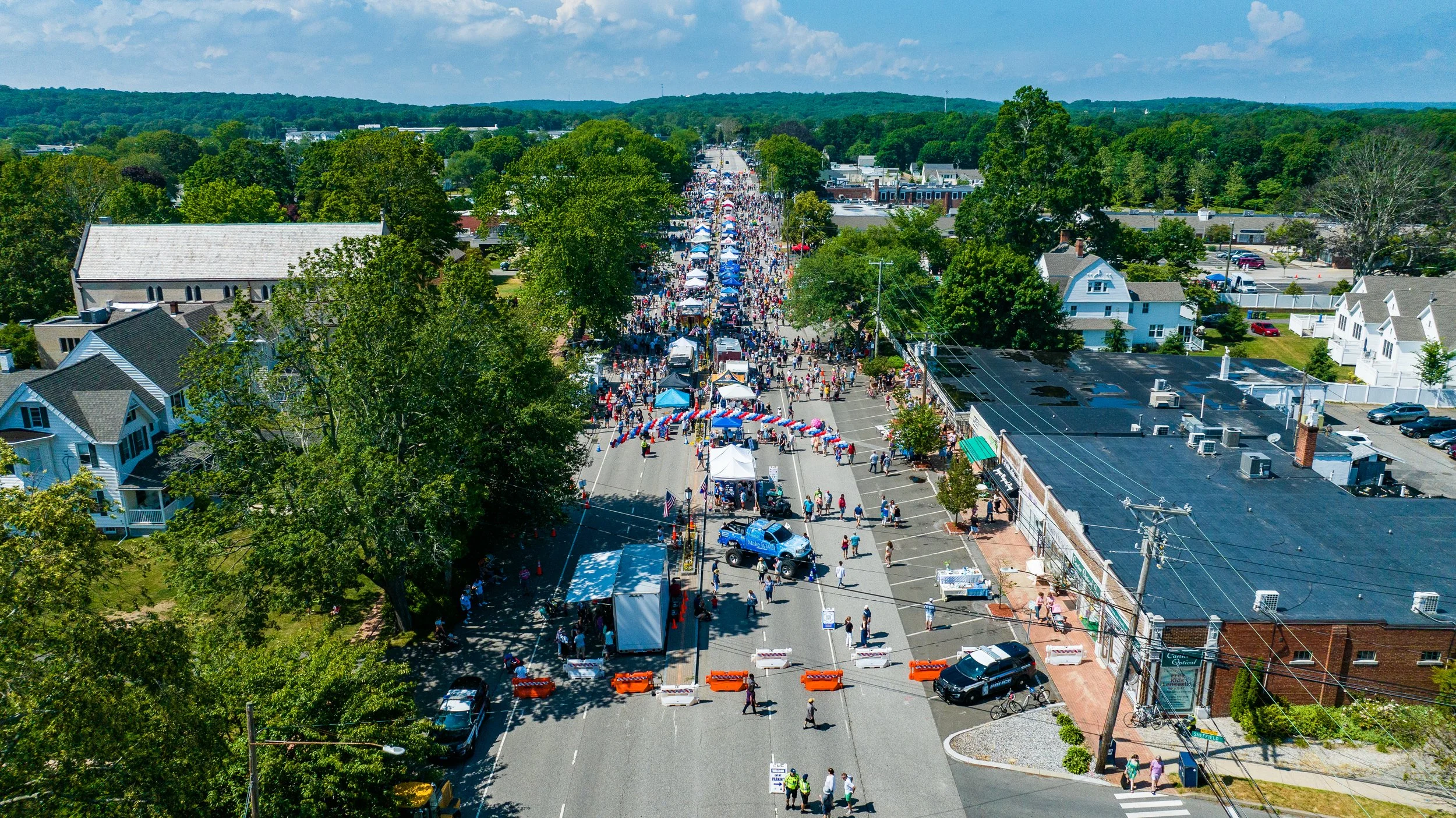 Aerial view of a street festival with tents and crowds.